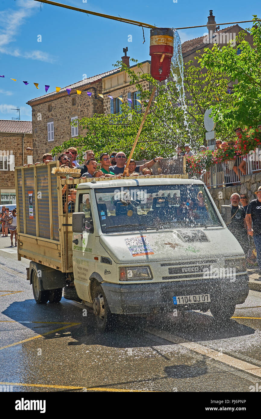 Saint Felicien and a white open back van passing under a water bucket as part of the festival of the goat and cheese Stock Photo