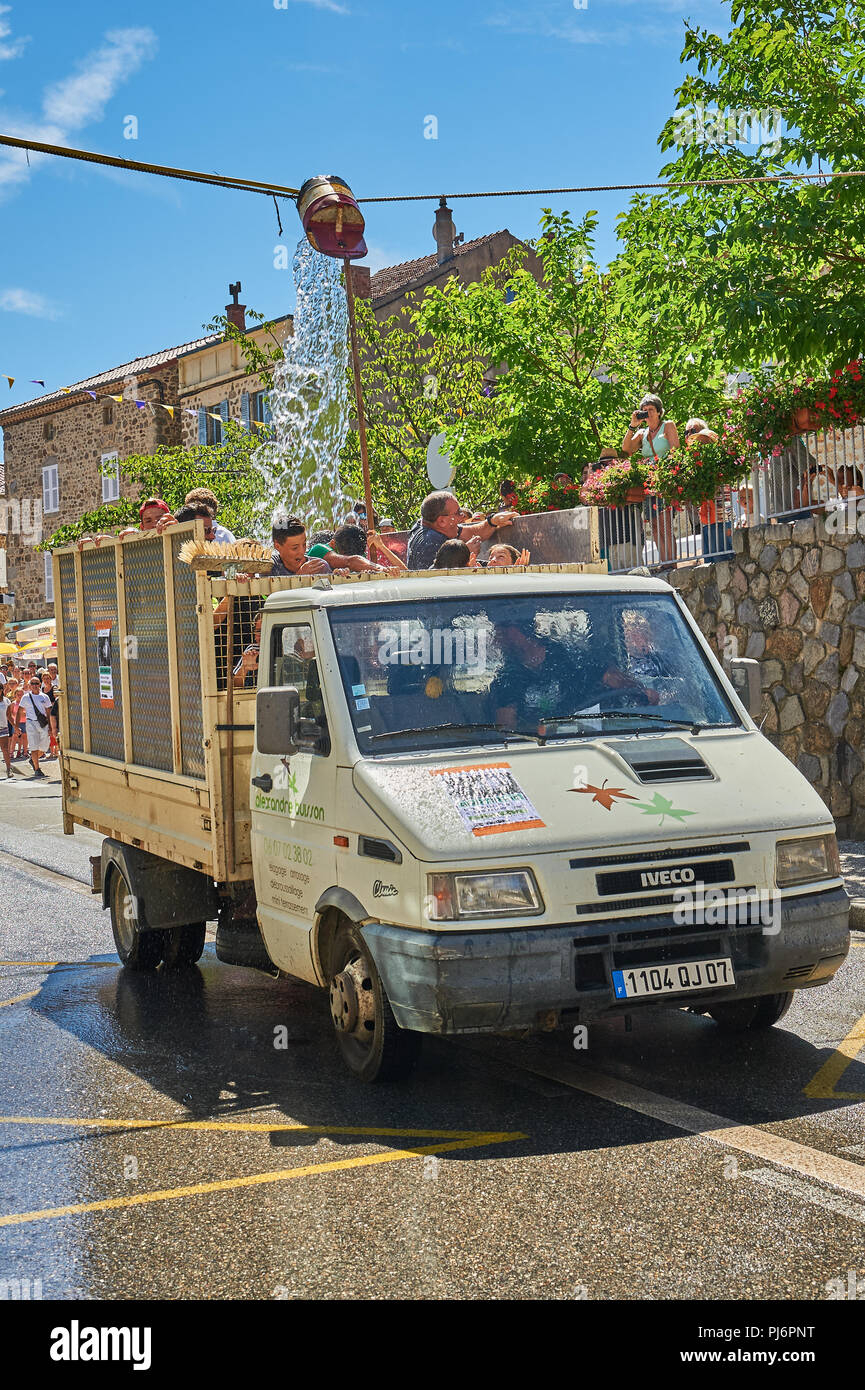 Saint Felicien and a white open back van passing under a water bucket as part of the festival of the goat and cheese Stock Photo
