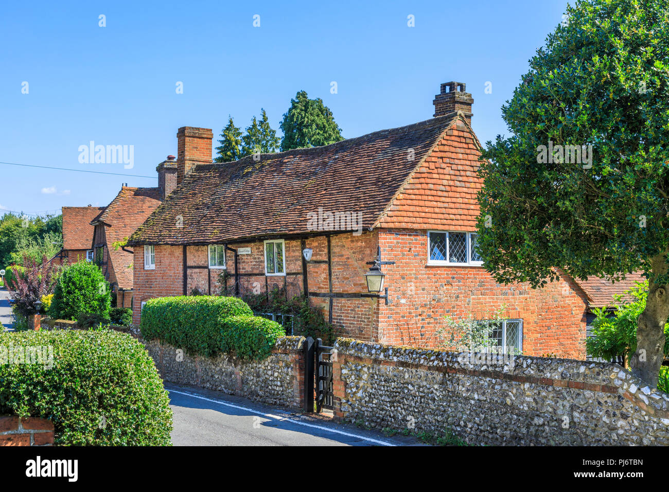 Pretty roadside redbrick Church Cottage with flint stone garden wall in East Clandon, a small village in Surrey near Guildford, southeast England Stock Photo