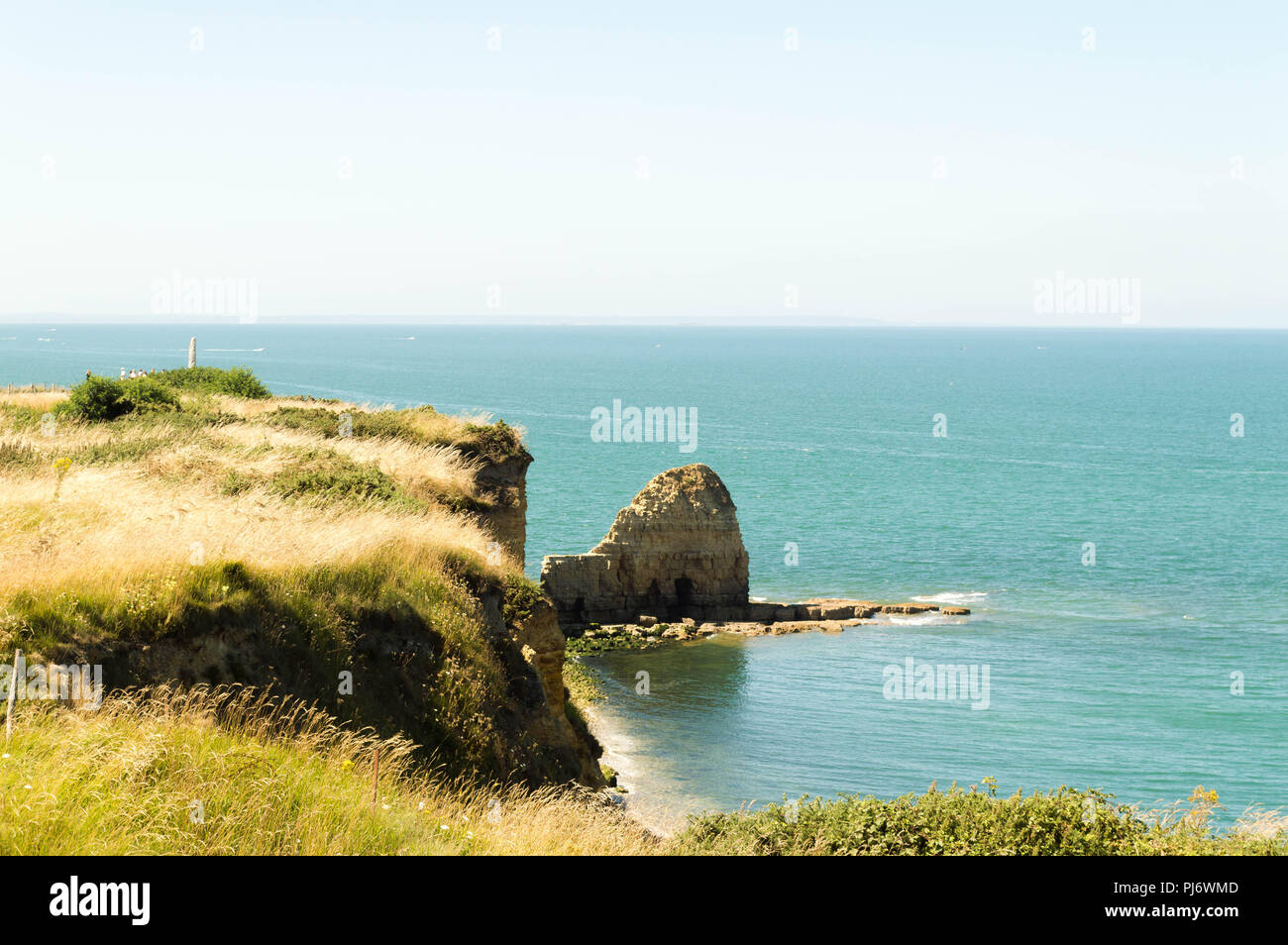 Cliff at seaside on a sunny day with burnt grass and rocks Stock Photo