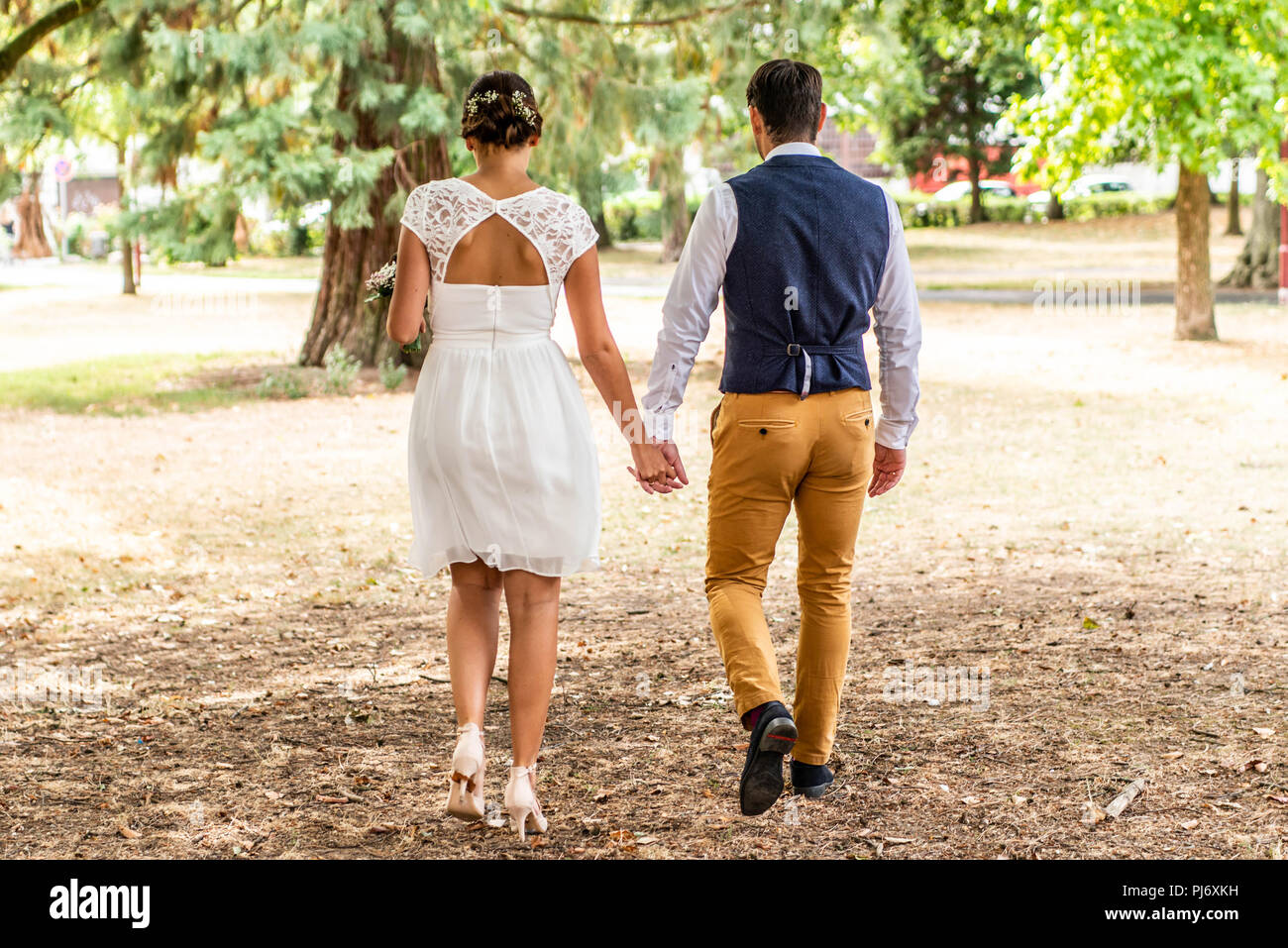 Bride and groom holding hand and walk in the garden Stock Photo - Alamy