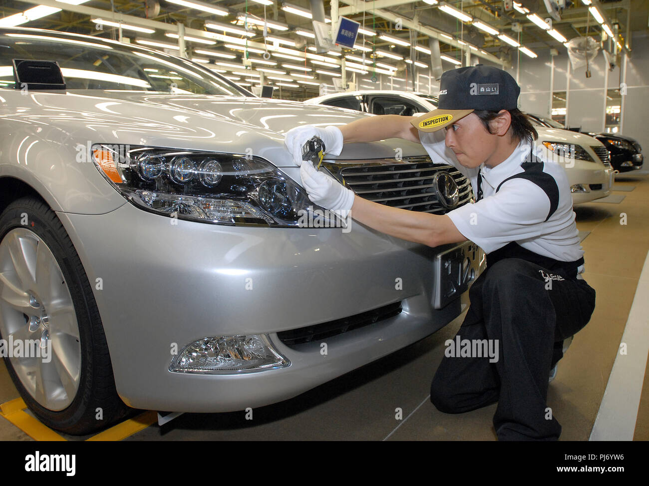 A worker inspects the body of a Toyota Motor Corp. Lexus vehicle for irregularities in panel fitting at the company's plant in Toyohashi City, Japan o Stock Photo