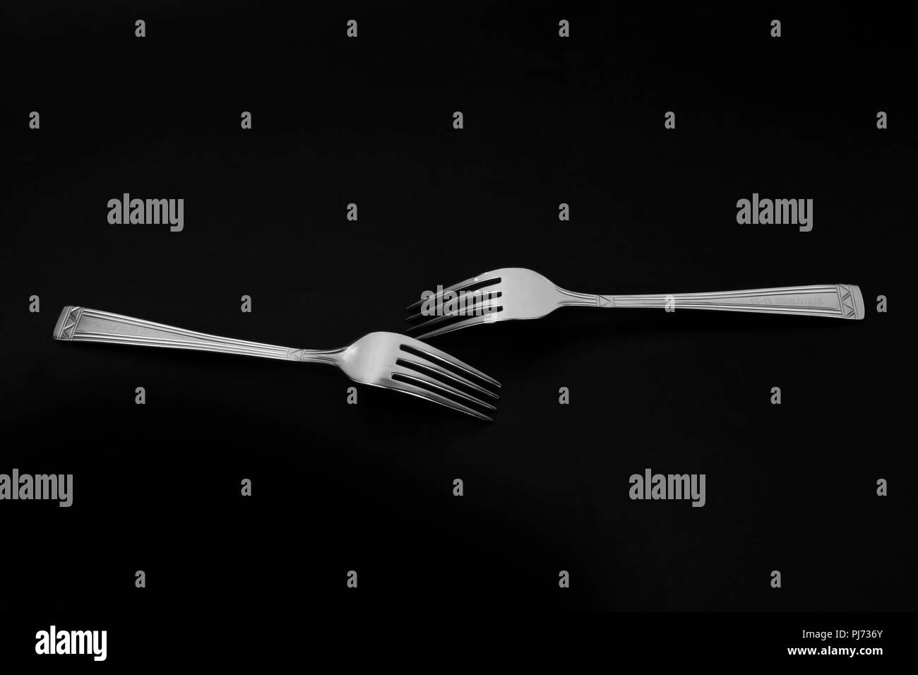 Two forks in on the black background in the studio. Stock Photo