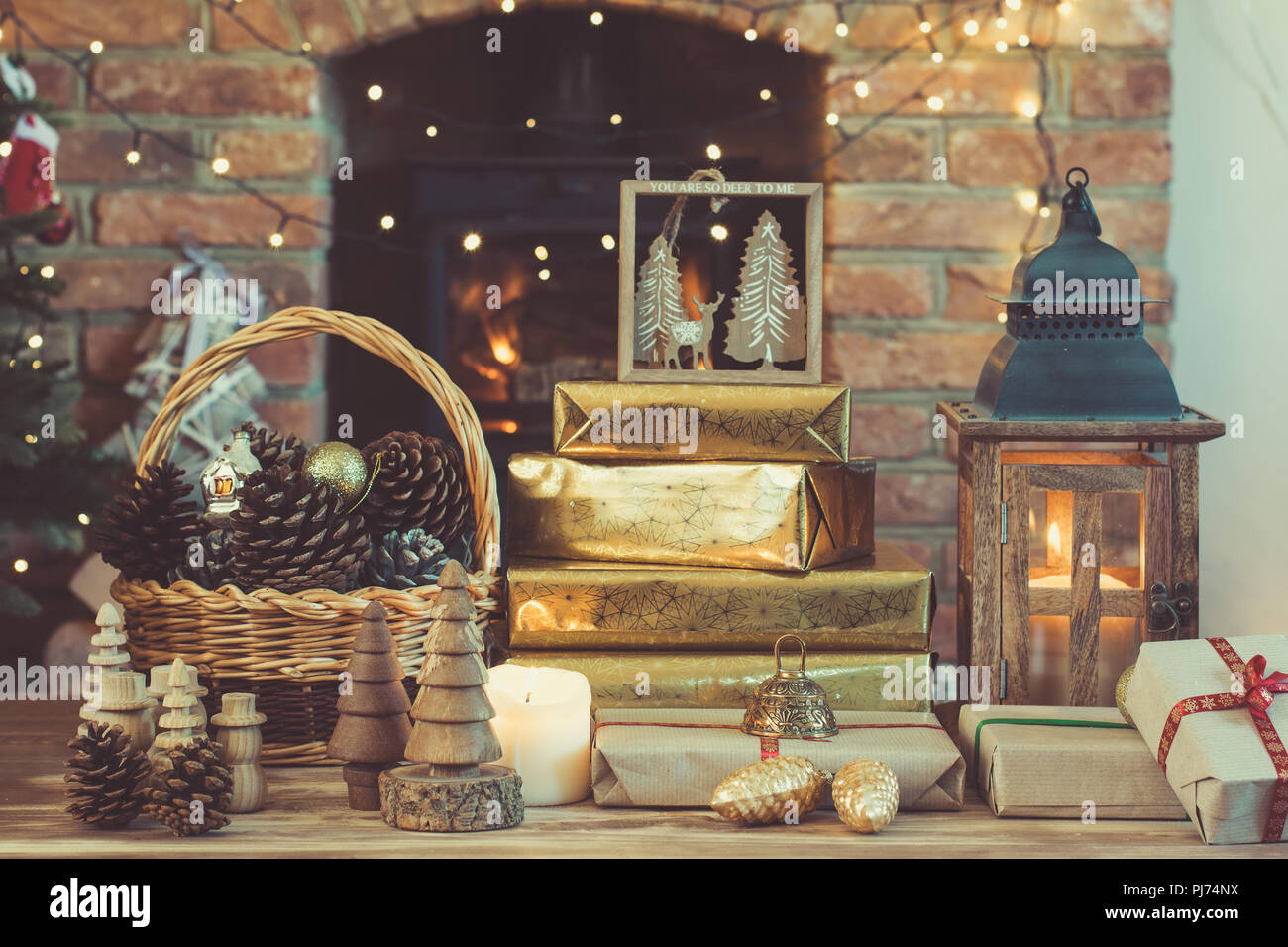 Dark Christmas composition, lantern, presents and handmade wooden  decorations on the table in front of fireplace with woodburner, ornaments  and garlan Stock Photo - Alamy