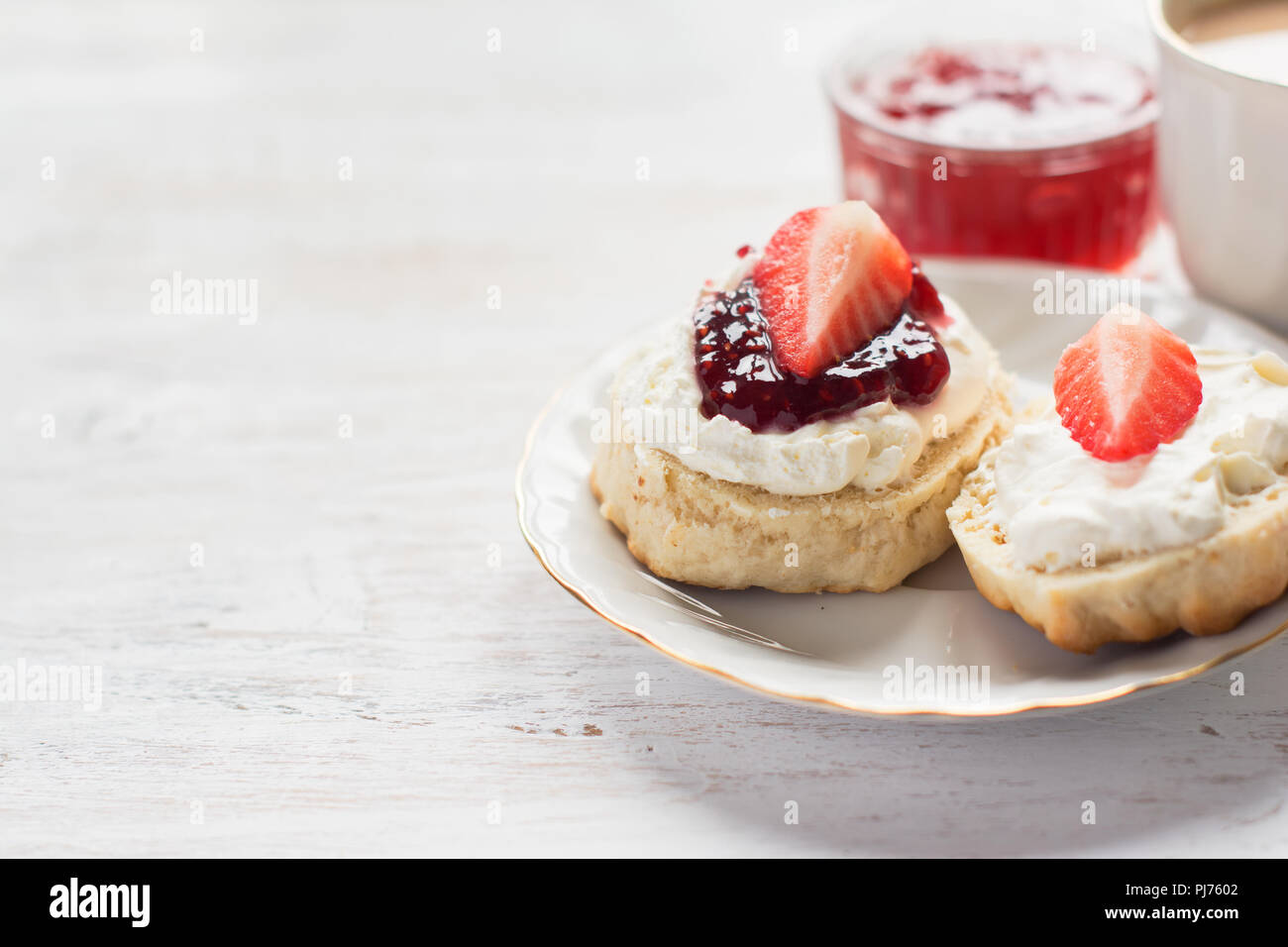 Cream teas with scones and clotted cream, raspberry jam, strawberries on the white table, copy space for text, selective focus Stock Photo