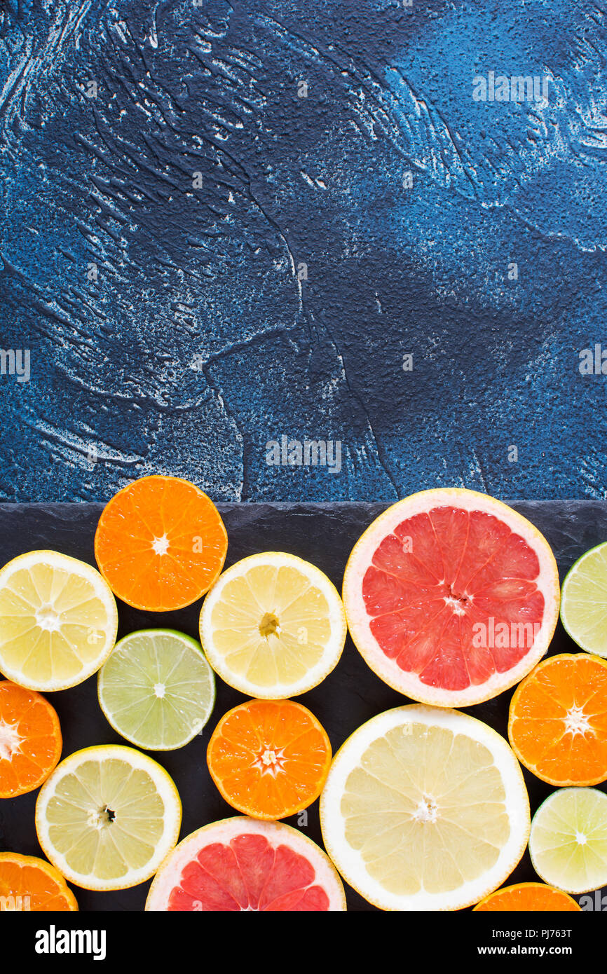 Satsumas, lemons, grapefruits and limes on the black slate on the dark