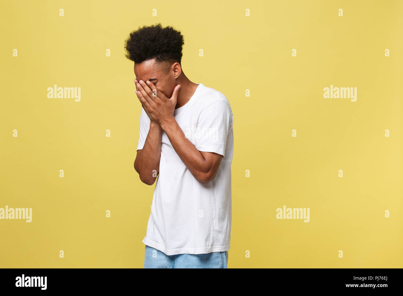Closeup portrait man with sad expression, isolated on yellow wall background. Human emotions, body language, life perception. Duh moment. Stock Photo