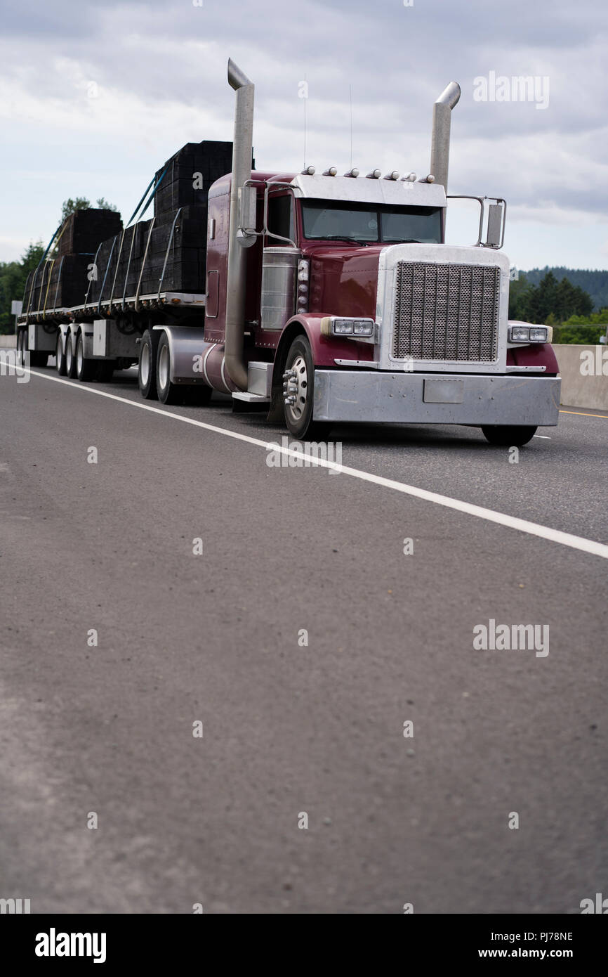 Transportation of overall equipment, building materials and other various industrial raw materials on flat bed semi trailers of mainline big rig semi  Stock Photo