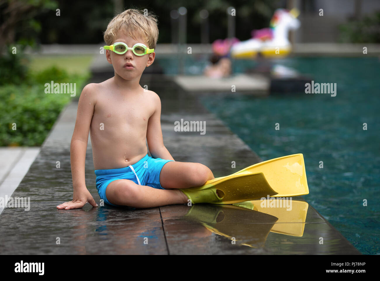Boy wearing goggles and flippers at the poolside being ready for a swim