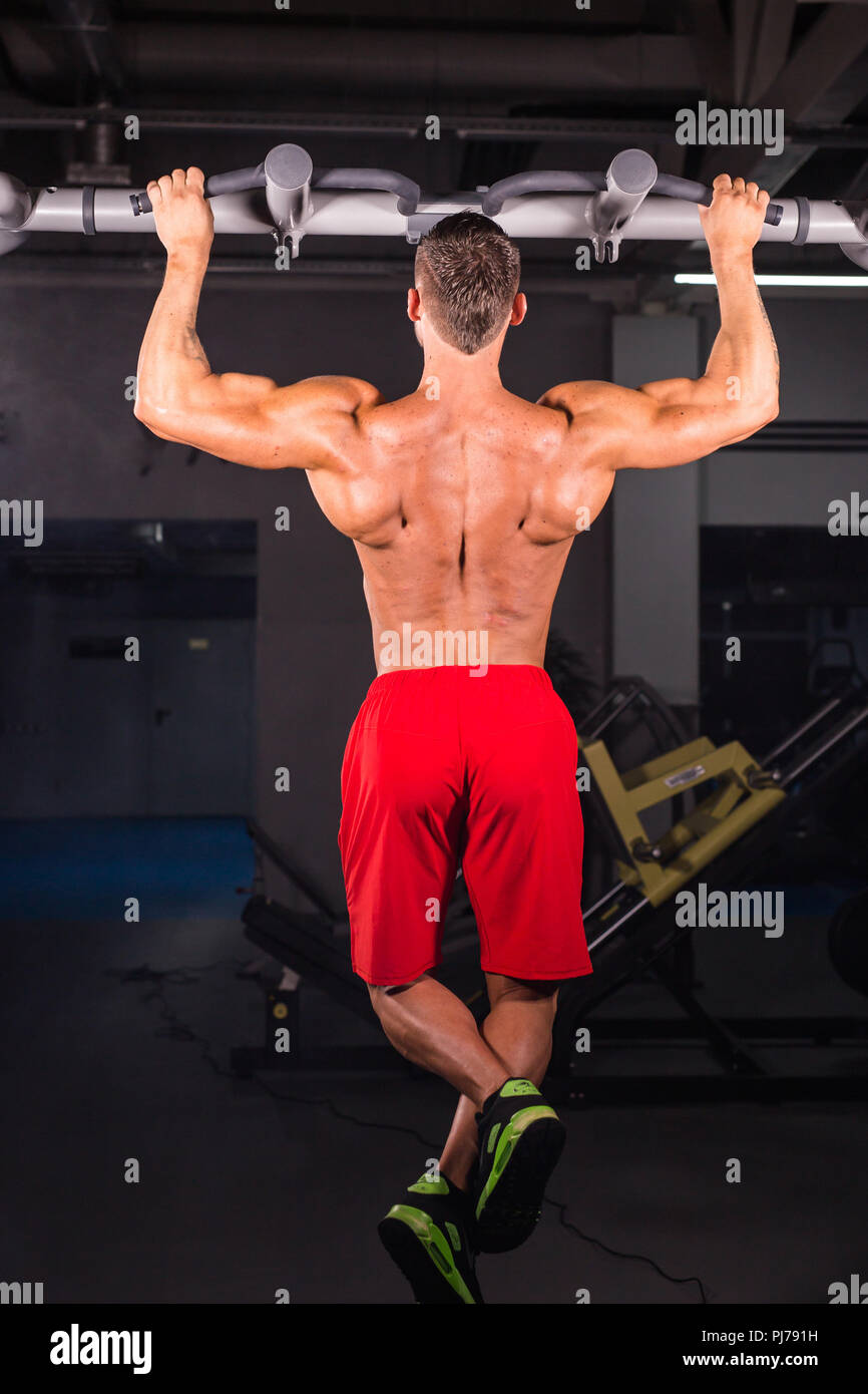 Strong young man doing pull up exercise on horizontal bar in gym Stock ...