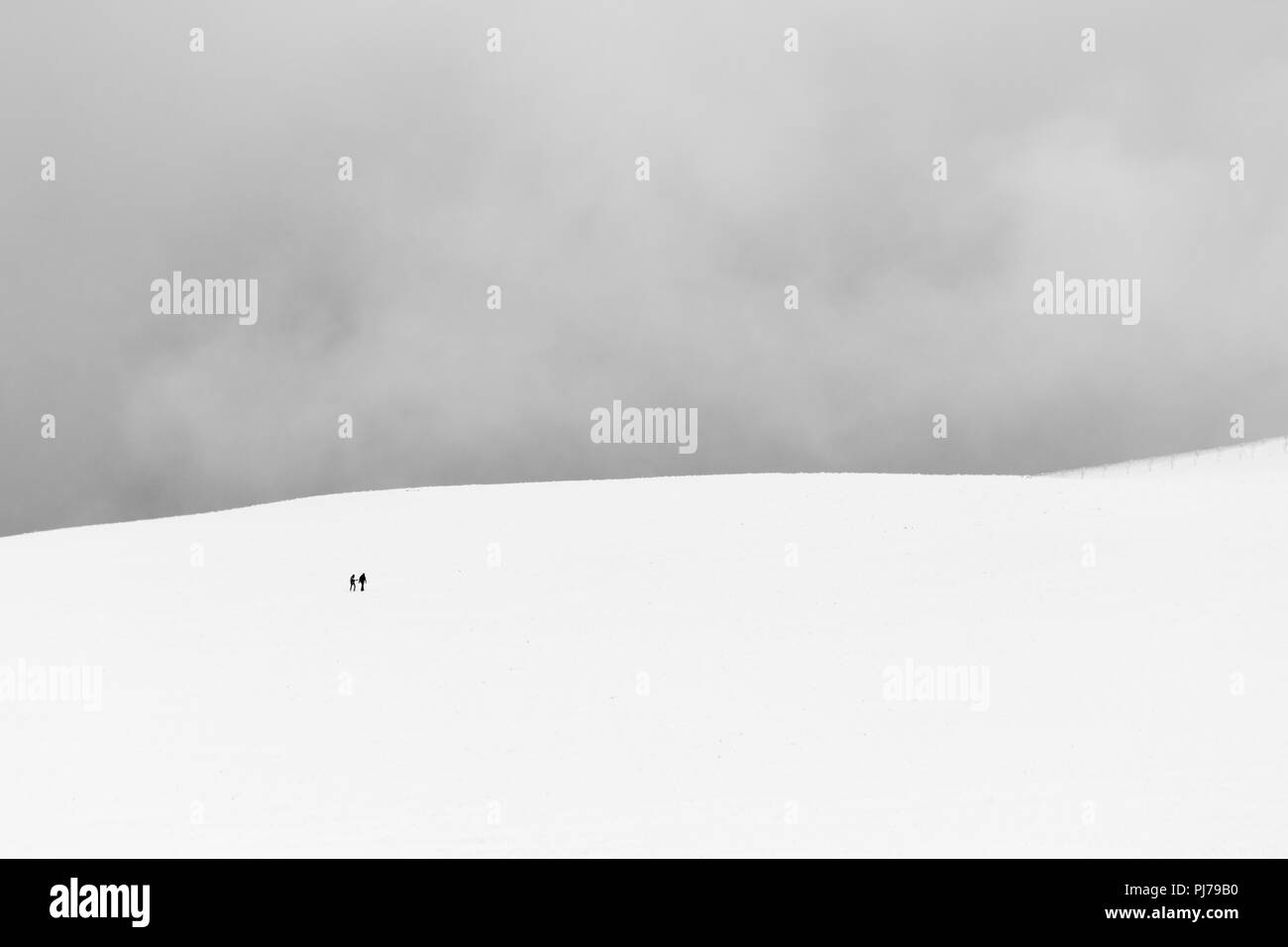 A very minimalistic view of two distant people over a mountain covered by snow Stock Photo