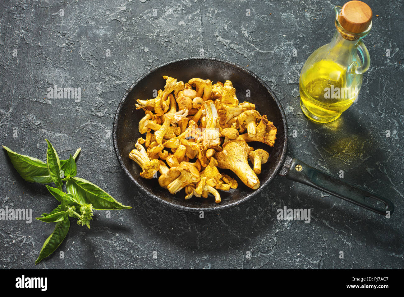 Fresh chanterelle mushrooms in a pan on a black stone table. Stock Photo
