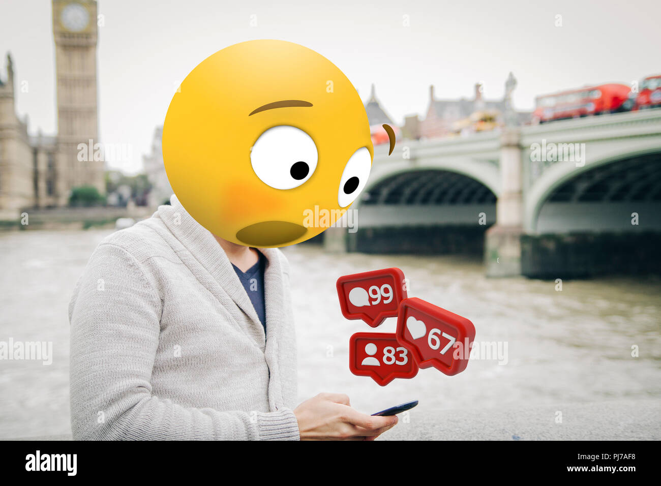 man with emoji head surprised looking at the smartphone al london city Stock Photo