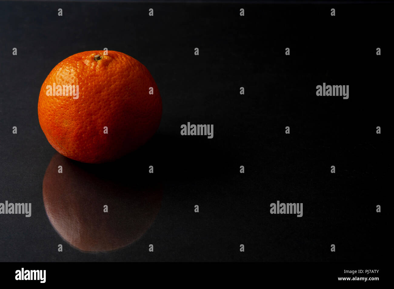 Mandarin orange isolated on dark black background with reflection ...