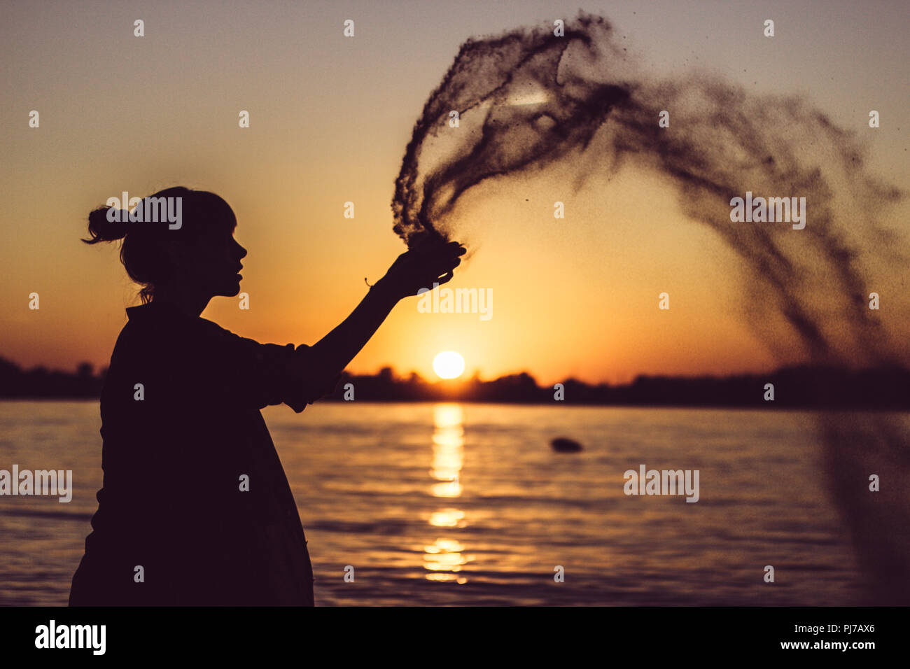 Woman playing with sand on beach with sunset Stock Photo