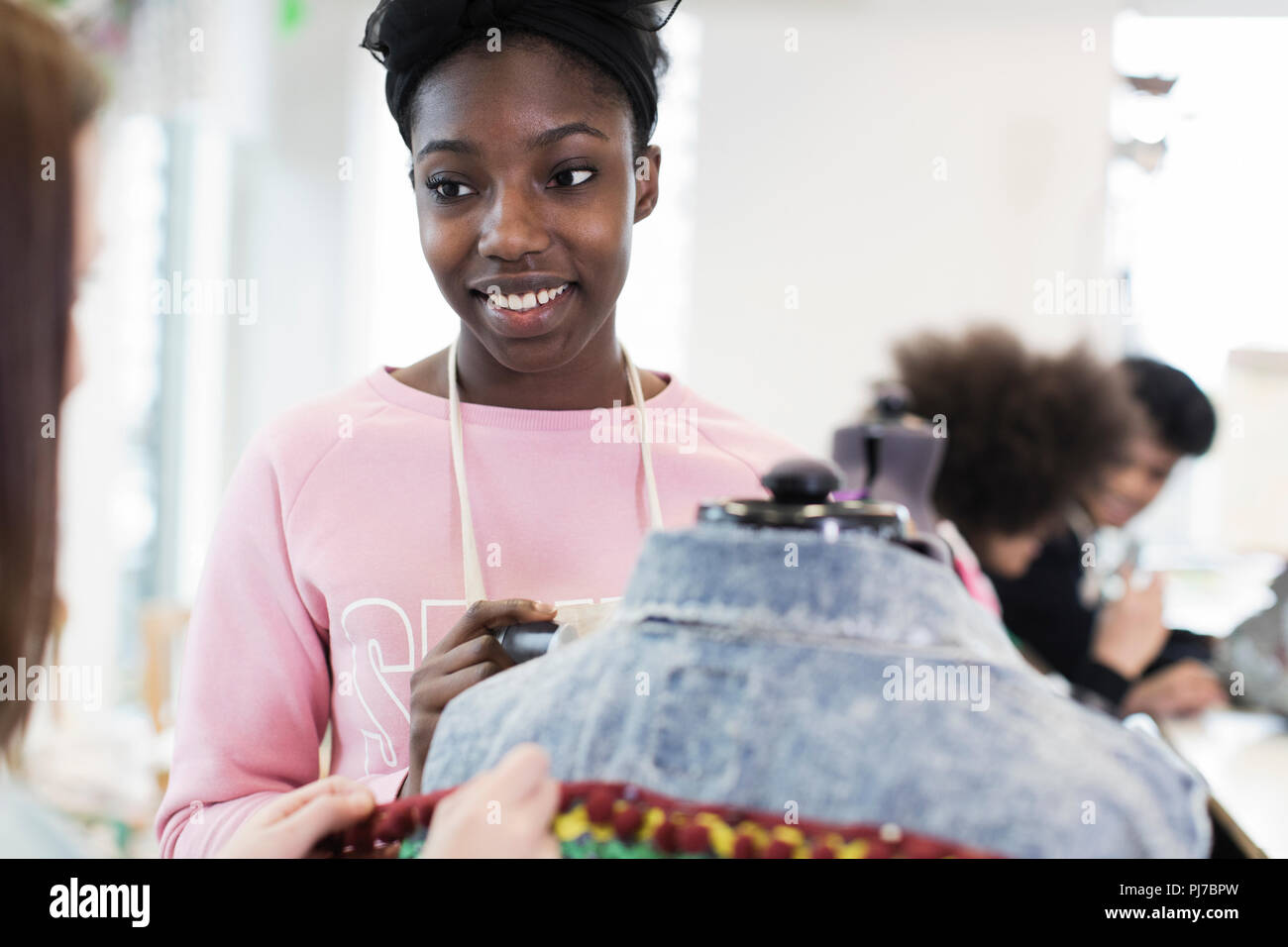 Smiling teenage girl designing denim jacket in fashion design class Stock Photo