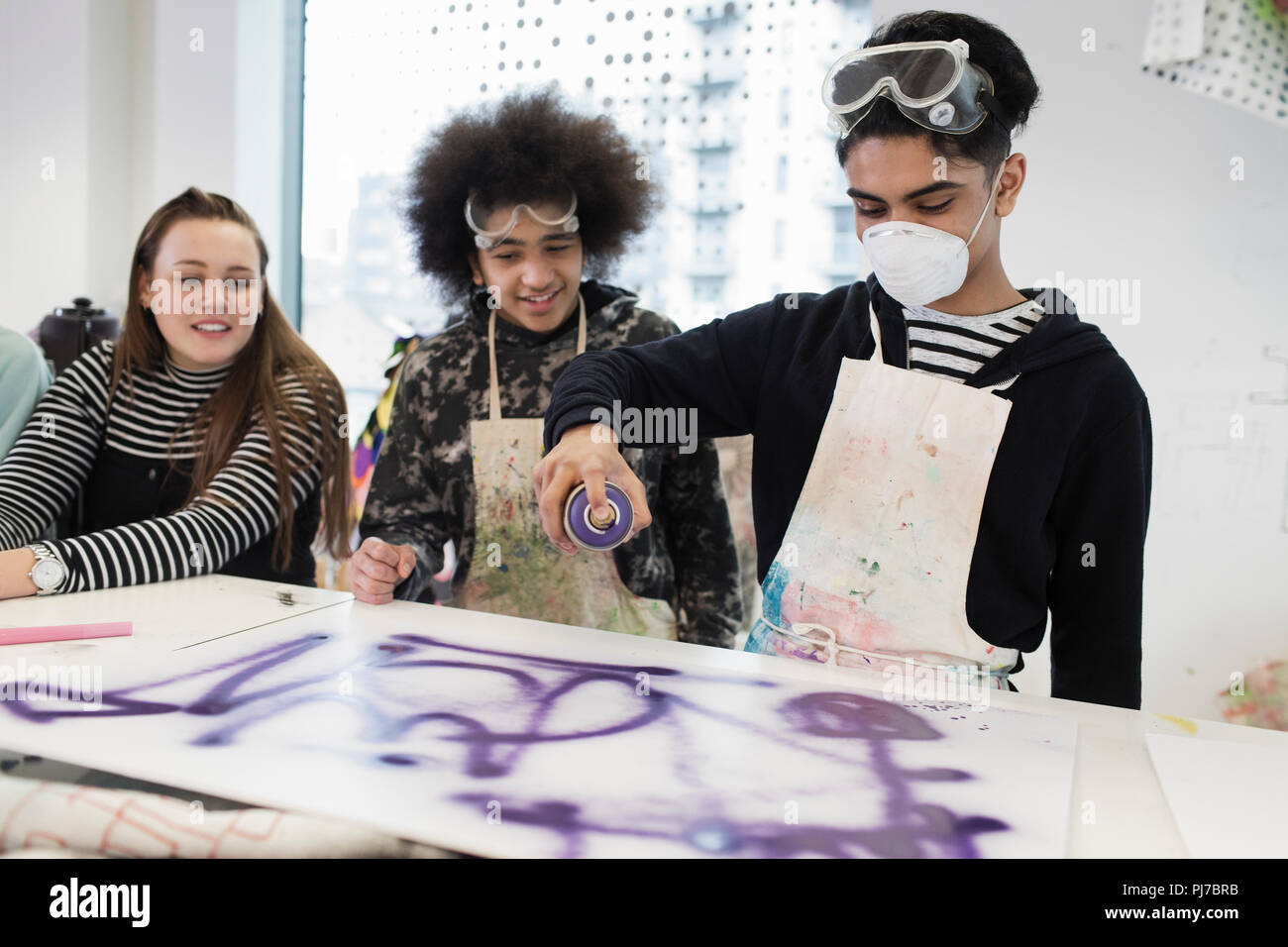 Teenagers spray painting in art class Stock Photo