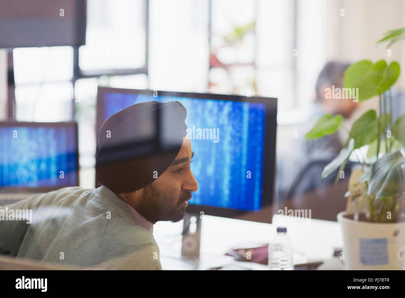 Indian computer programmer in turban working in office Stock Photo