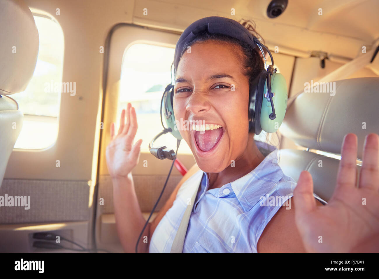 Portrait enthusiastic young woman with headphones riding in airplane Stock Photo
