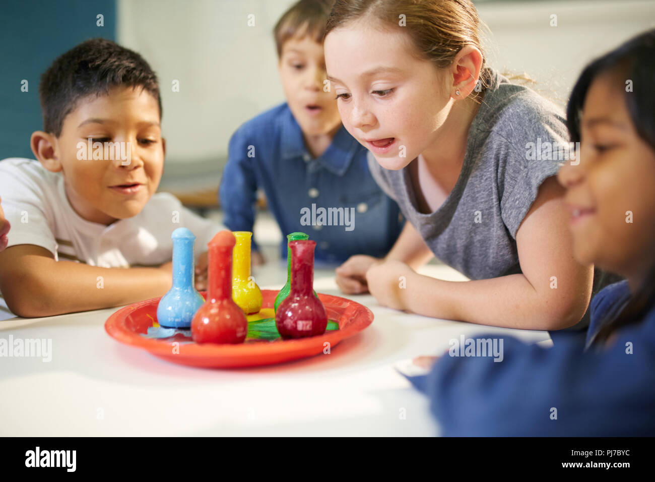 Curious kids watching multicolor foam in beakers Stock Photo