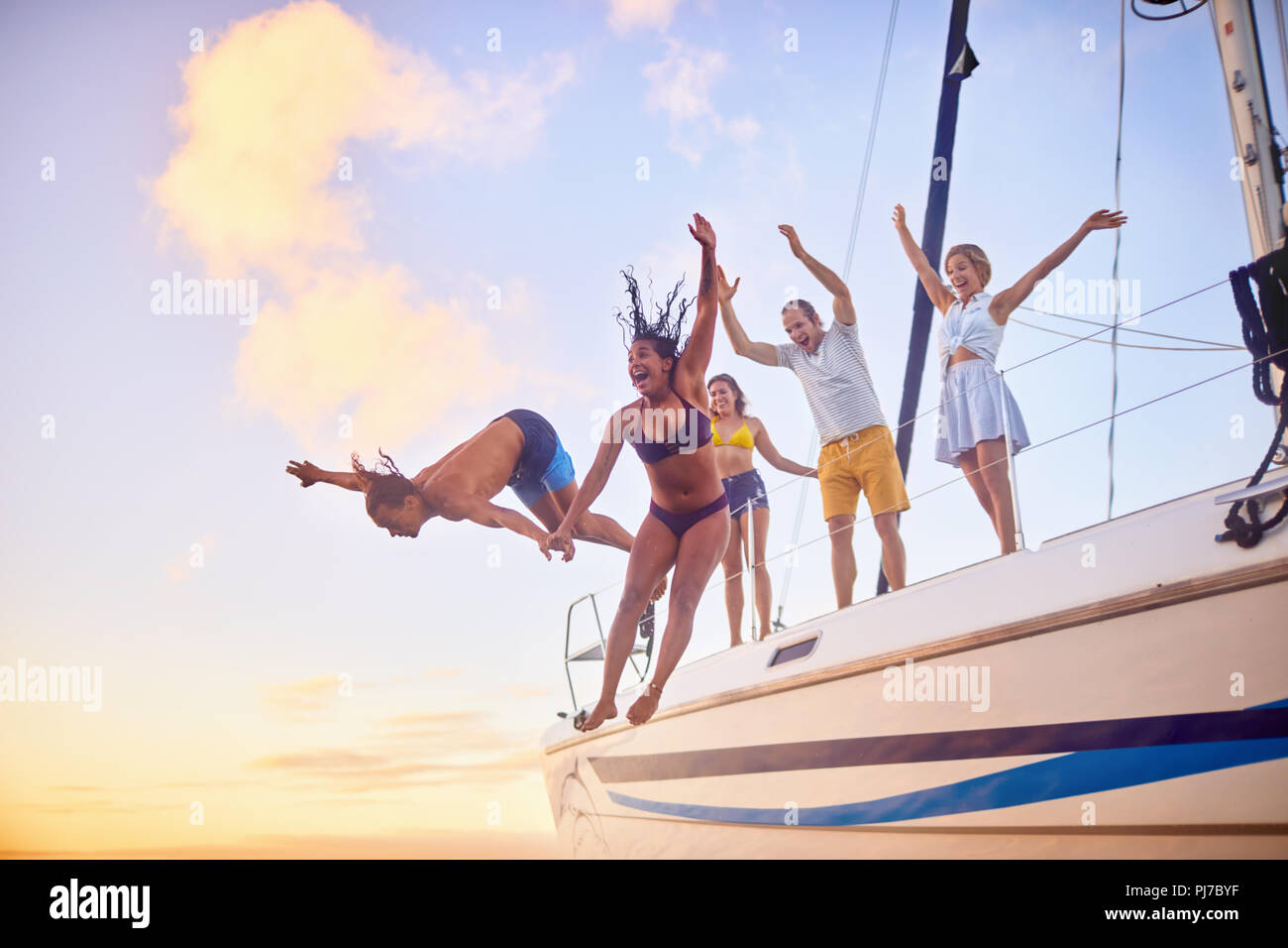 Playful friends jumping off boat Stock Photo