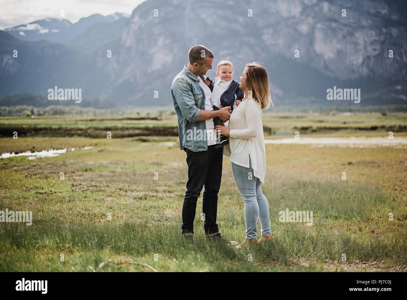 Parents and baby son standing in rural field Stock Photo