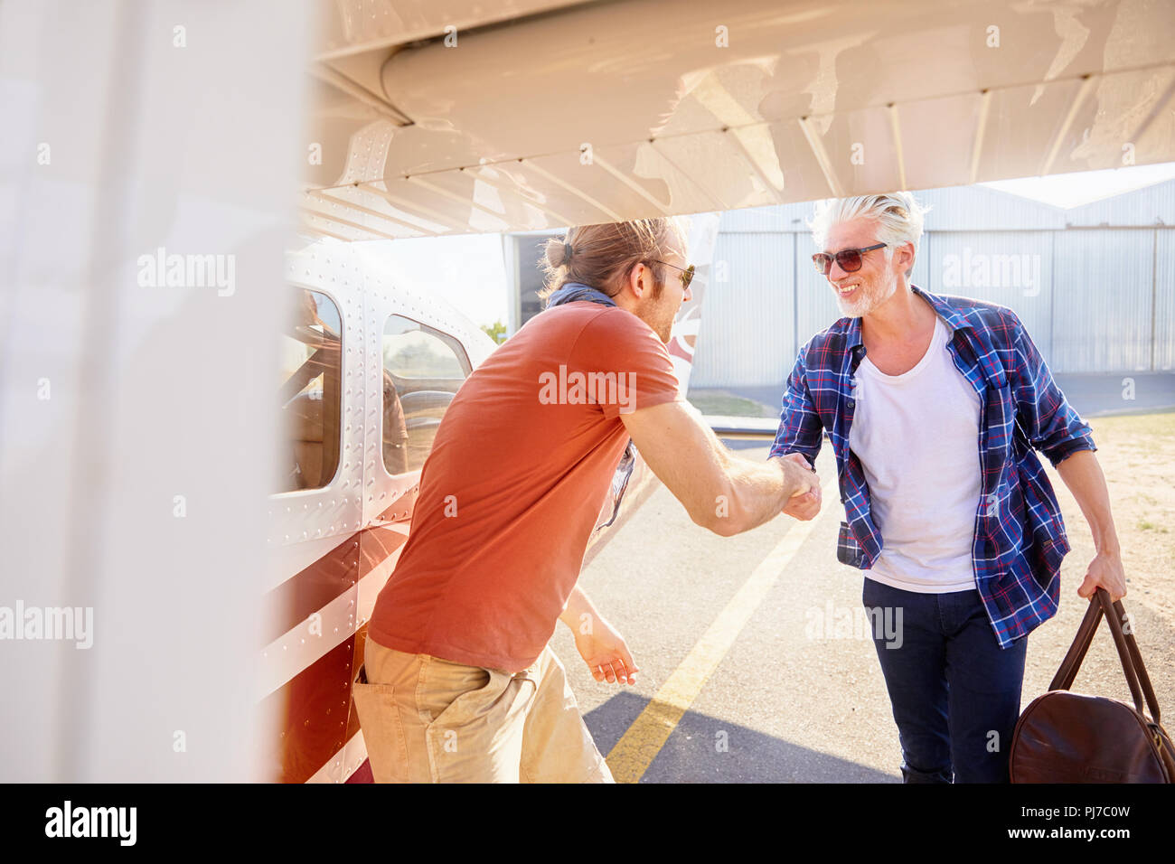 Pilot shaking hands with man boarding small airplane Stock Photo