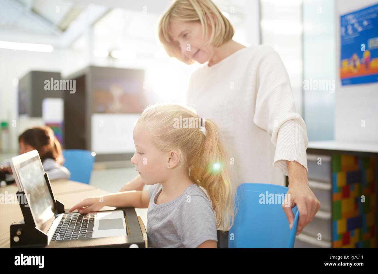 Teacher and schoolgirl using laptop in science center Stock Photo - Alamy