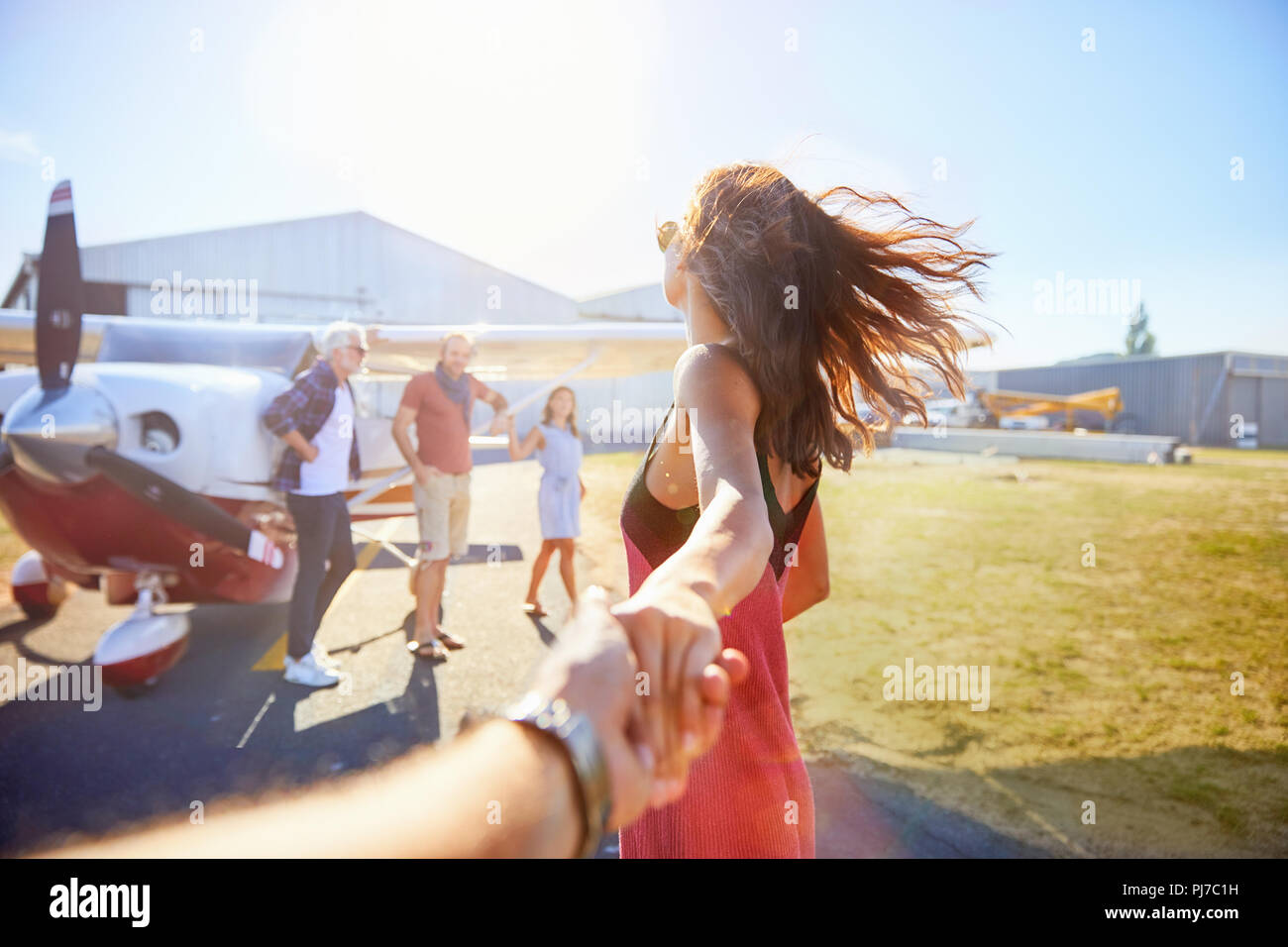 Personal perspective woman leading man by hand toward prop airplane Stock Photo