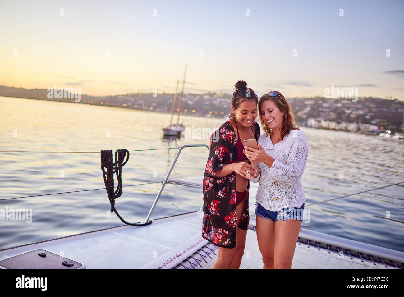 Young women using smart phone on catamaran Stock Photo