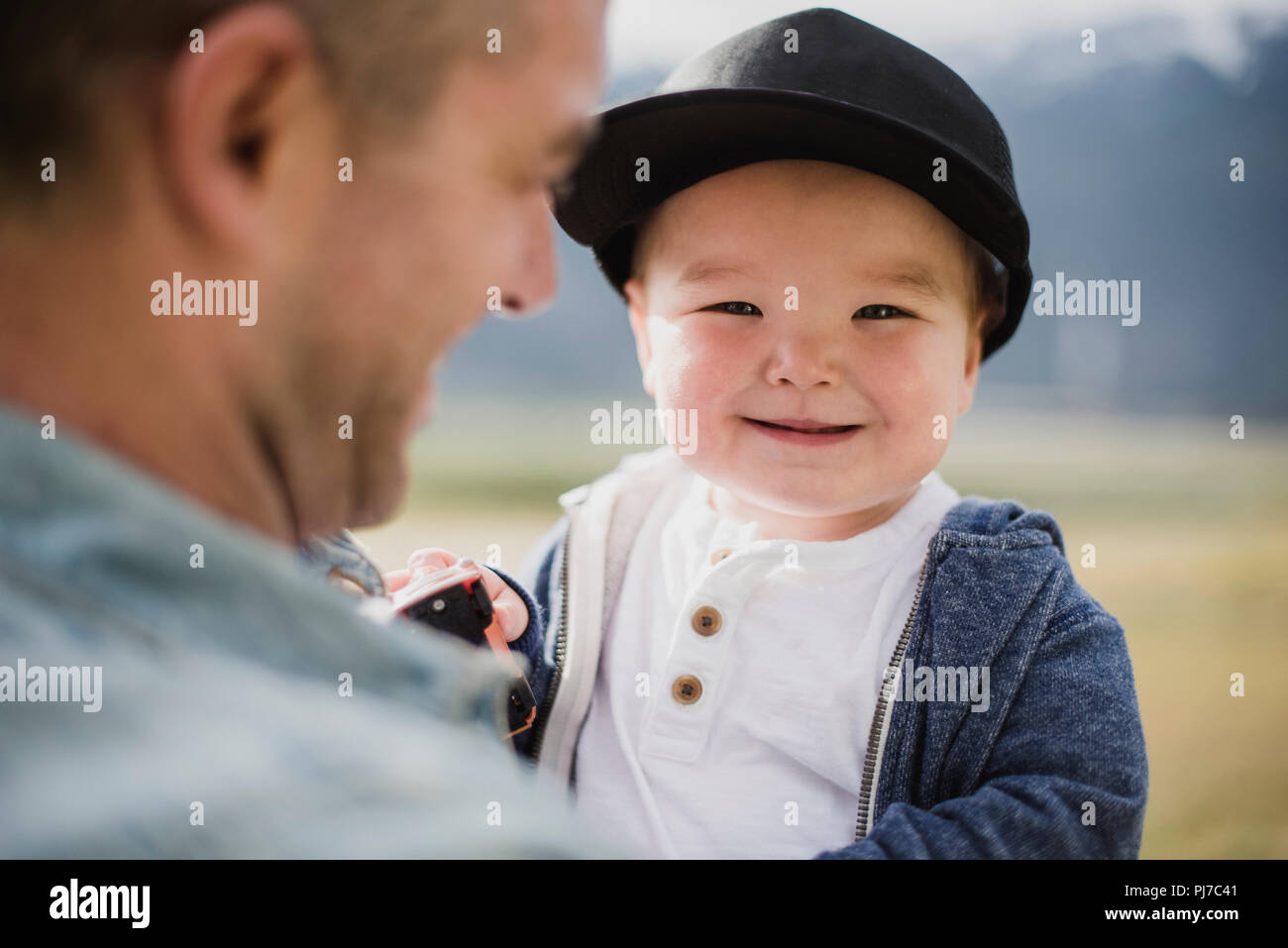 Portrait cute baby boy over father s shoulder Stock Photo
