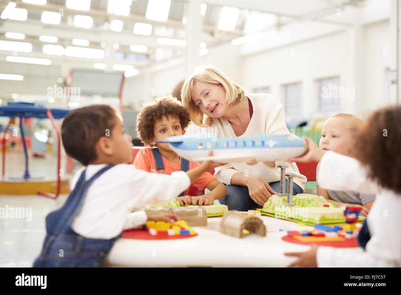 Teacher showing toy airplane to kids in science center Stock Photo