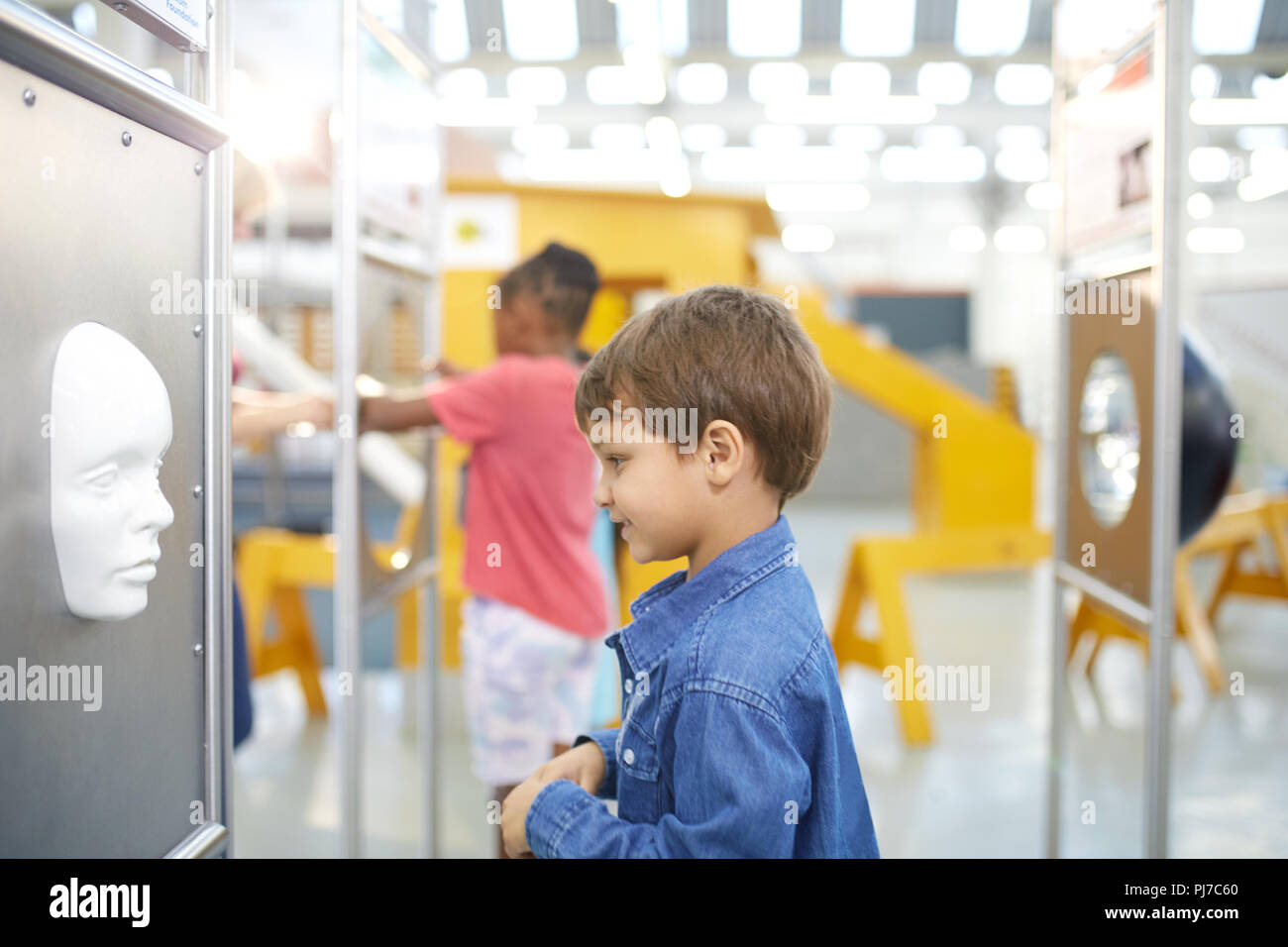 Curious boy looking at face in science center Stock Photo