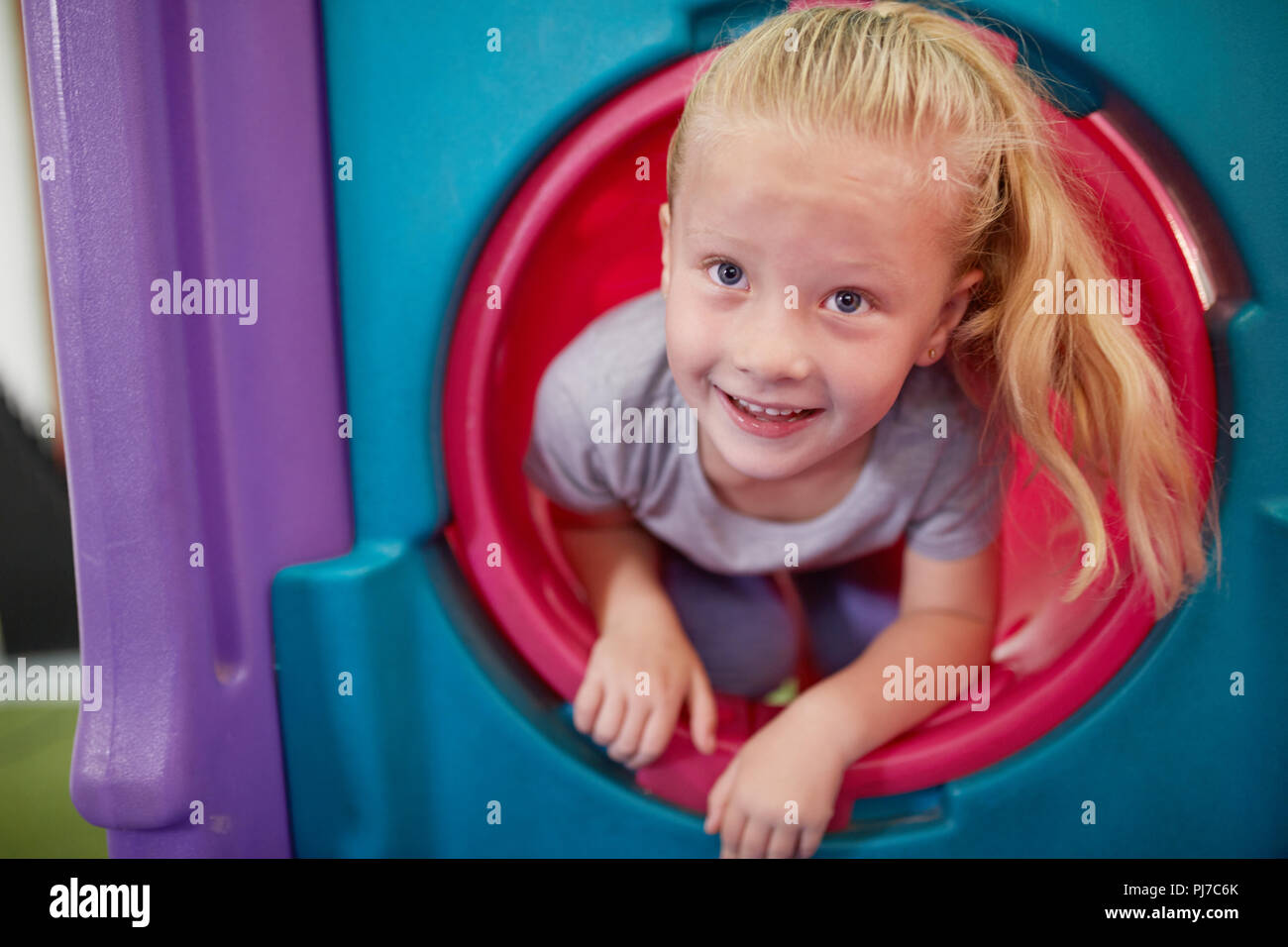 Portrait cute, happy girl playing in tube slide Stock Photo