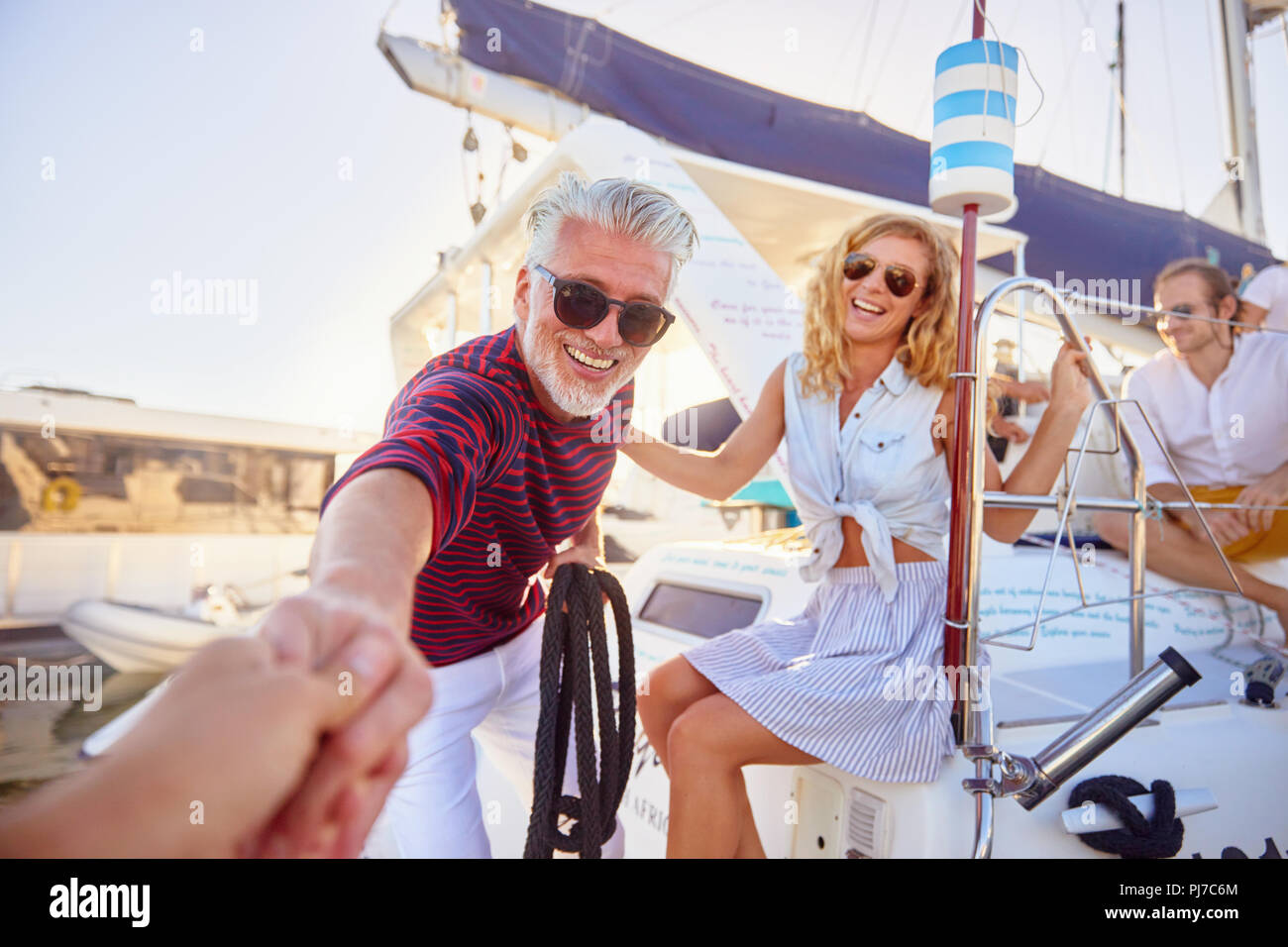 Personal perspective smiling man helping woman onto boat Stock Photo