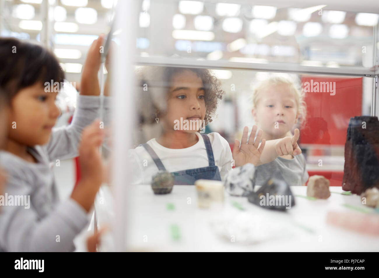 Curious kids looking at rocks in display case in science center Stock Photo