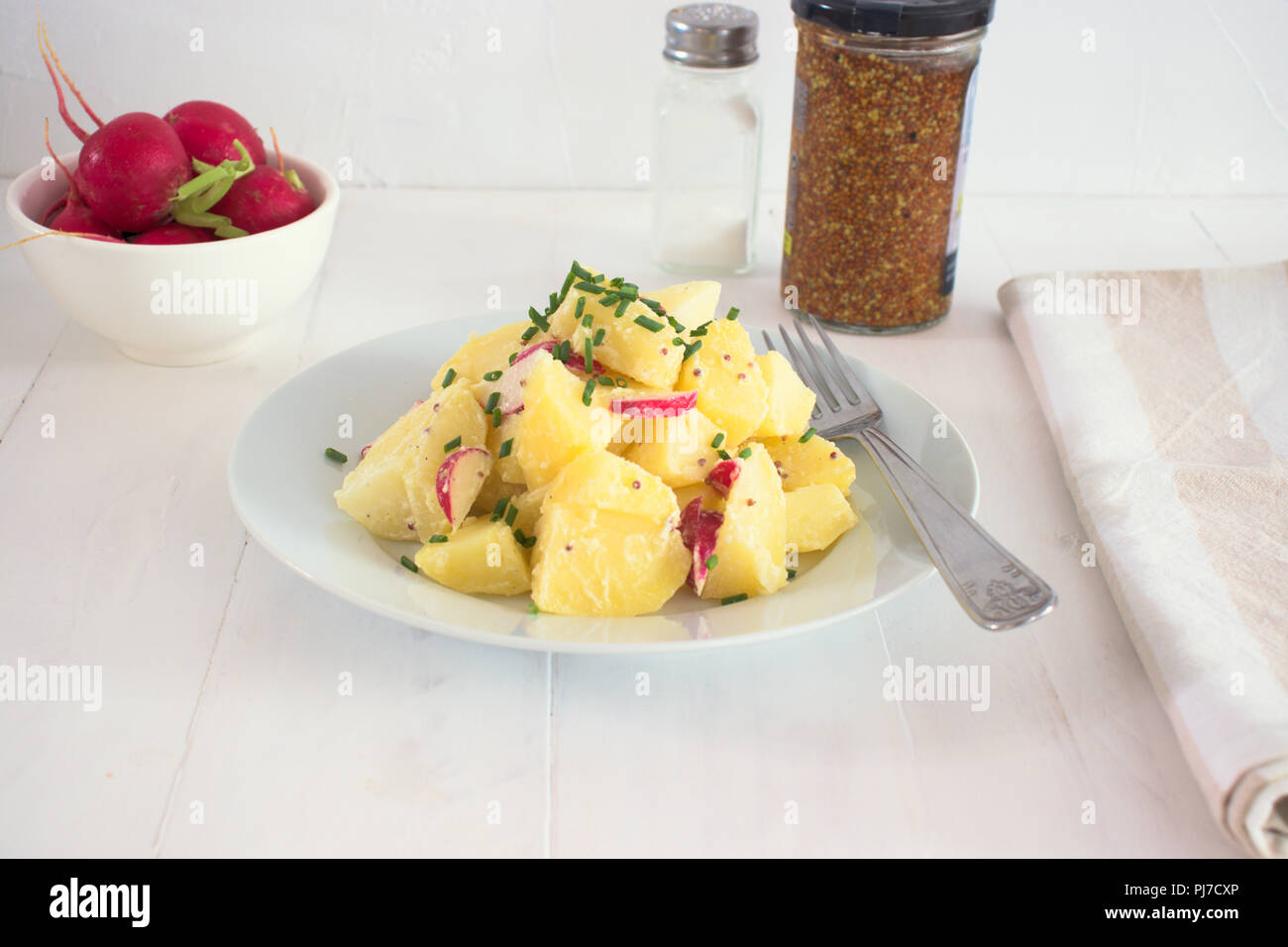 Healthy potato salad with radish and yogurt dressing seasoned with olive oil, mustard and lemon juice, with chives on top Stock Photo