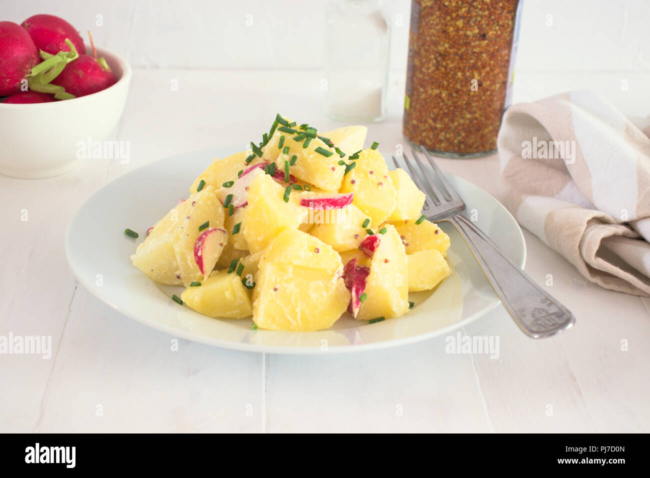 Healthy potato salad with radish and yogurt dressing seasoned with olive oil, mustard and lemon juice, with chives on top Stock Photo