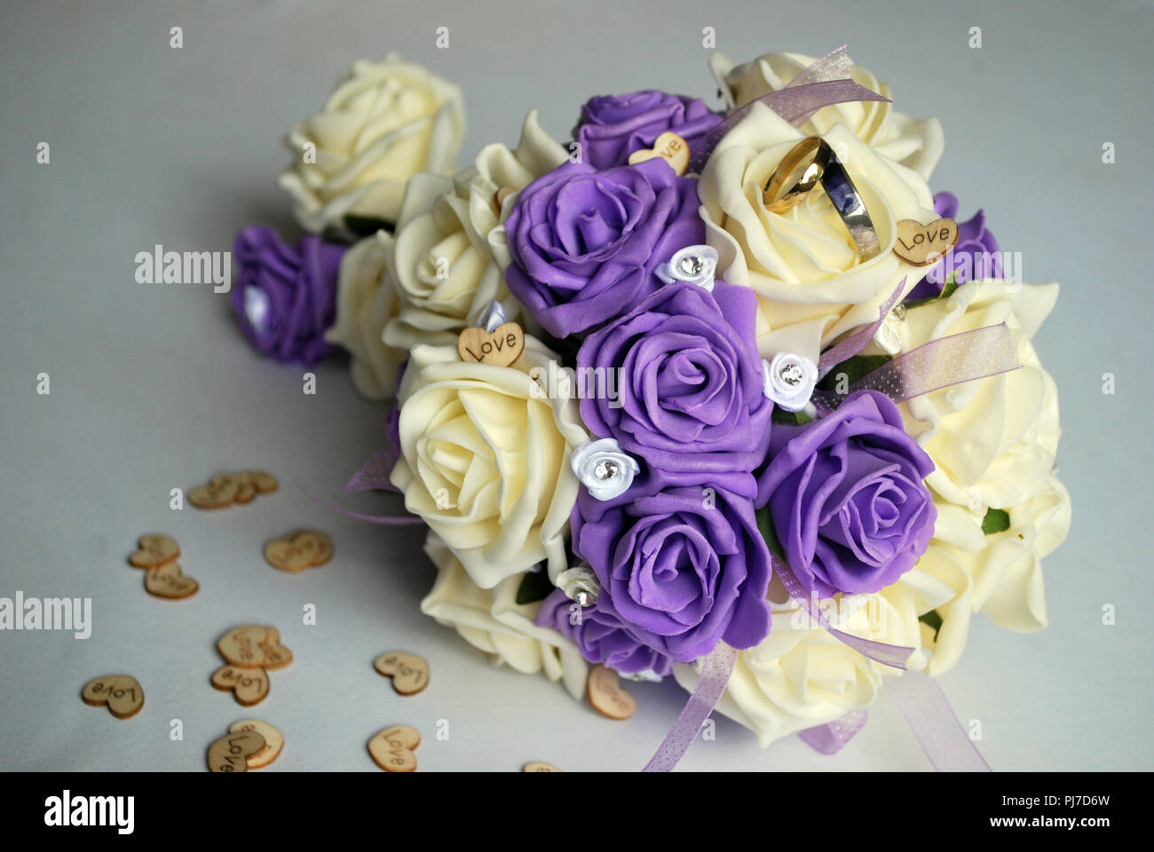 white and mauve rose bouquet with gold and silver wedding rings with inlaid blue john stone Stock Photo