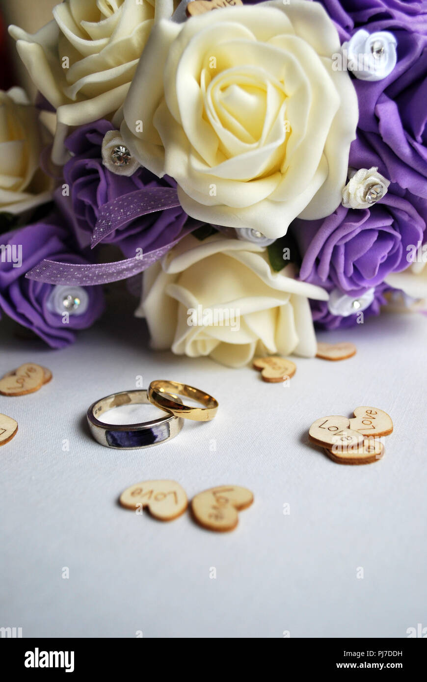 white and mauve rose bouquet with gold and silver wedding rings with inlaid blue john stone Stock Photo