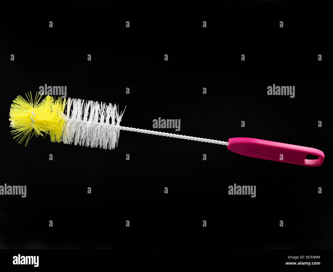 white and yellow bottle brush with pink handle isolated on black background. Stock Photo