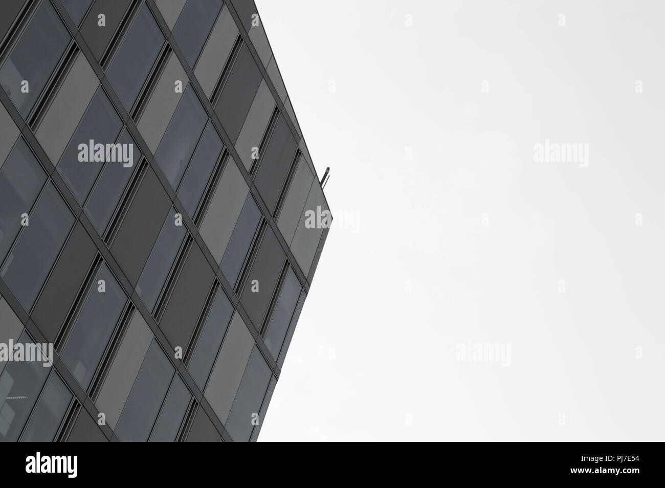 Minimalist architecture pointing into the sky with geommetrical lines and windows in black and white Stock Photo