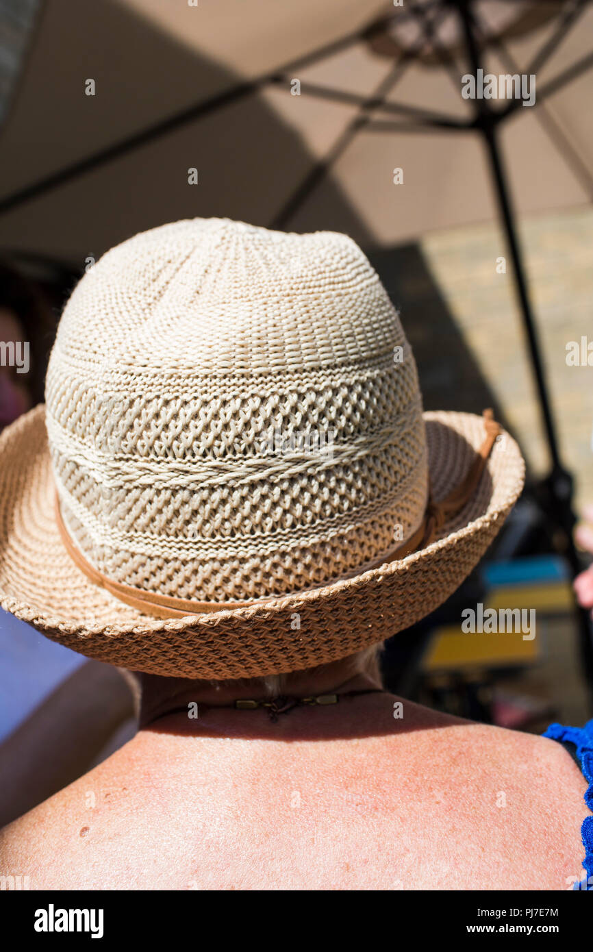 The back of a white female showing shoulders and a woven hat protecting her from the bright summer sunshine. Stock Photo
