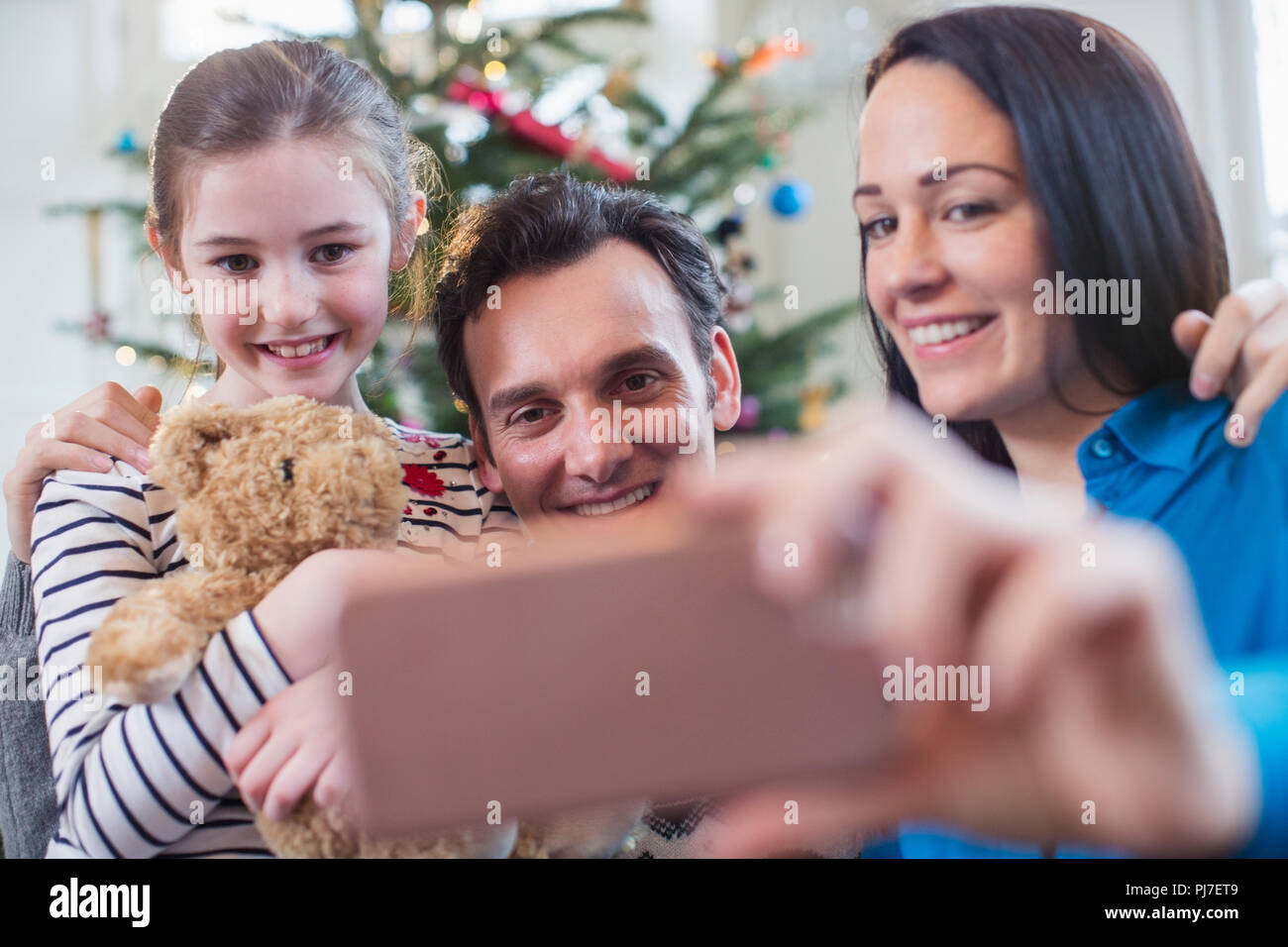 Happy family with smart phone taking selfie in Christmas living room Stock Photo