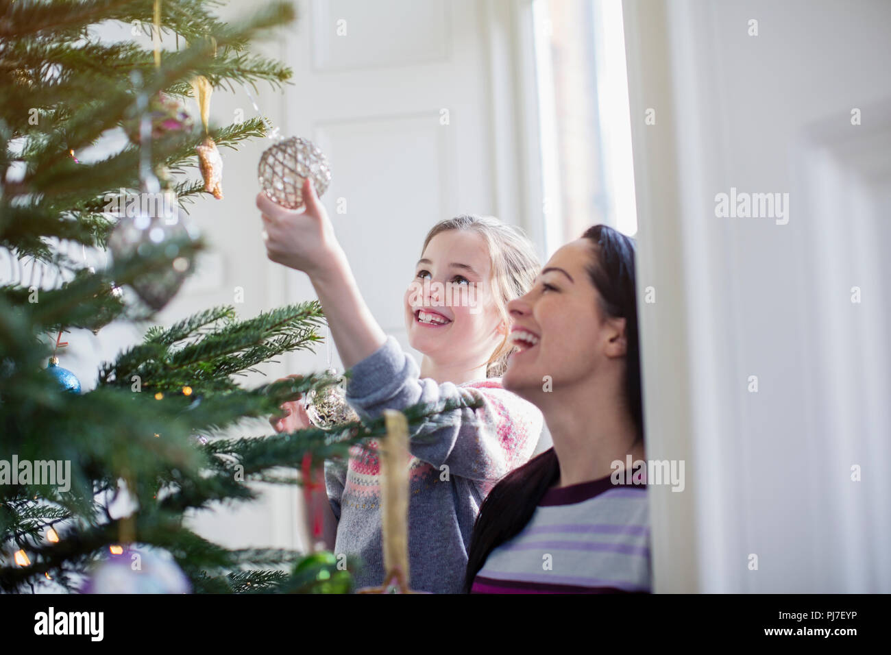 Happy mother and daughter decorating Christmas tree Stock Photo