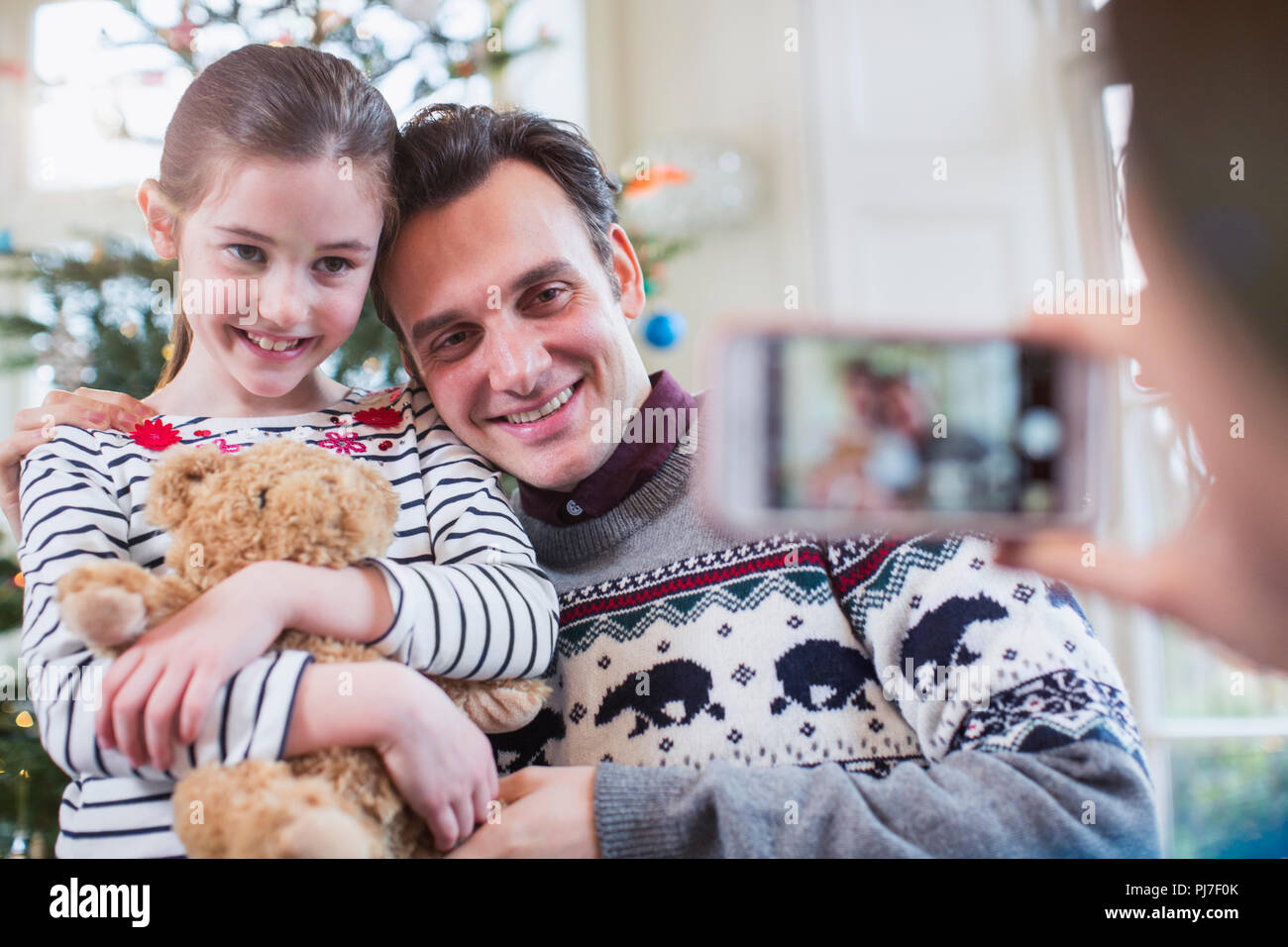 Father and daughter posing for photograph in Christmas living room Stock Photo