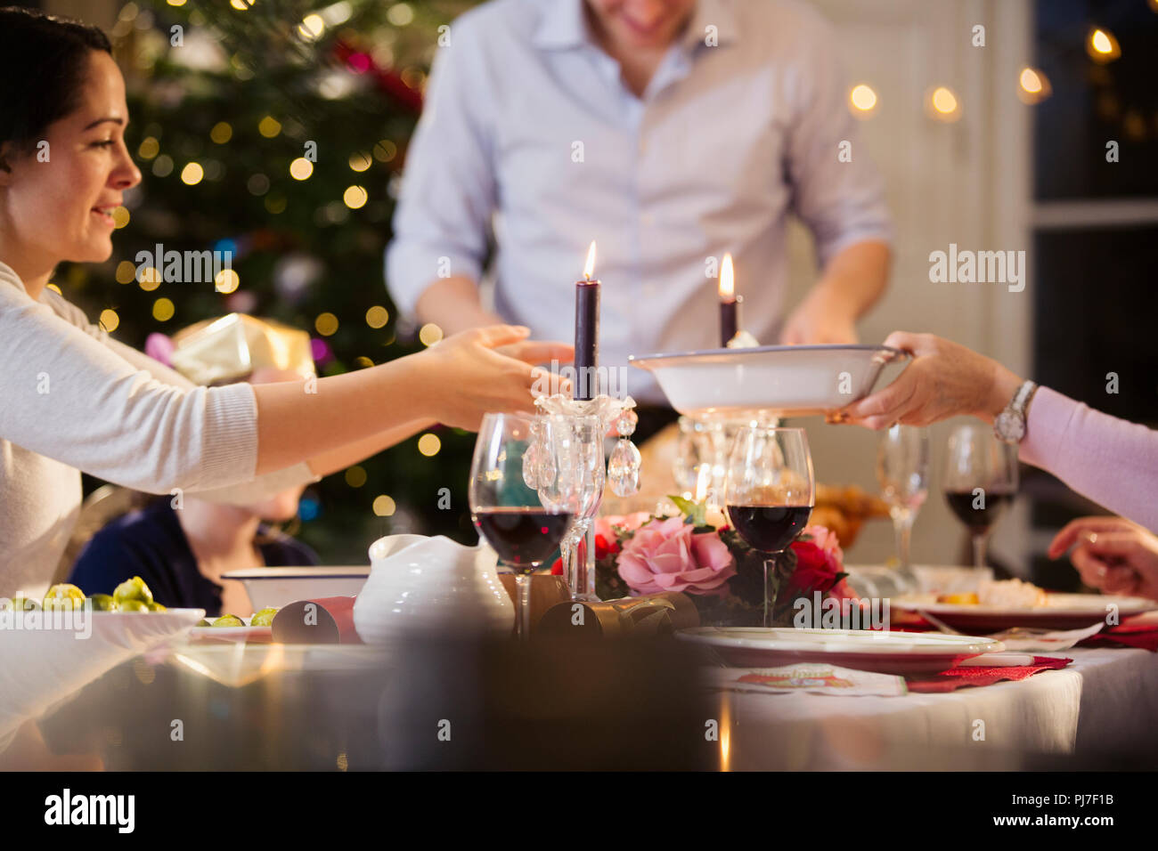 Family passing food, enjoying candlelight Christmas dinner Stock Photo