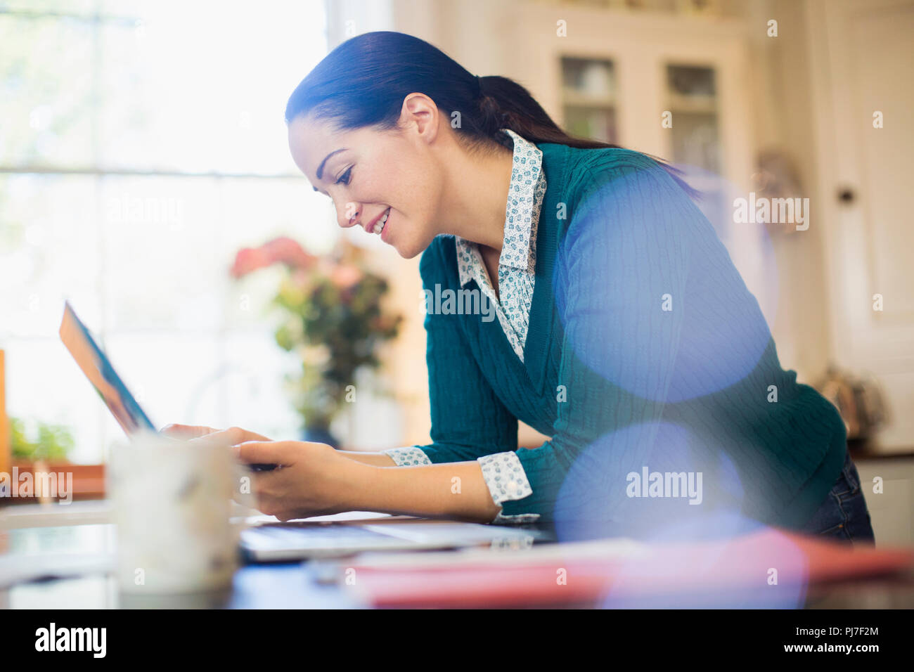 Woman using laptop in kitchen Stock Photo