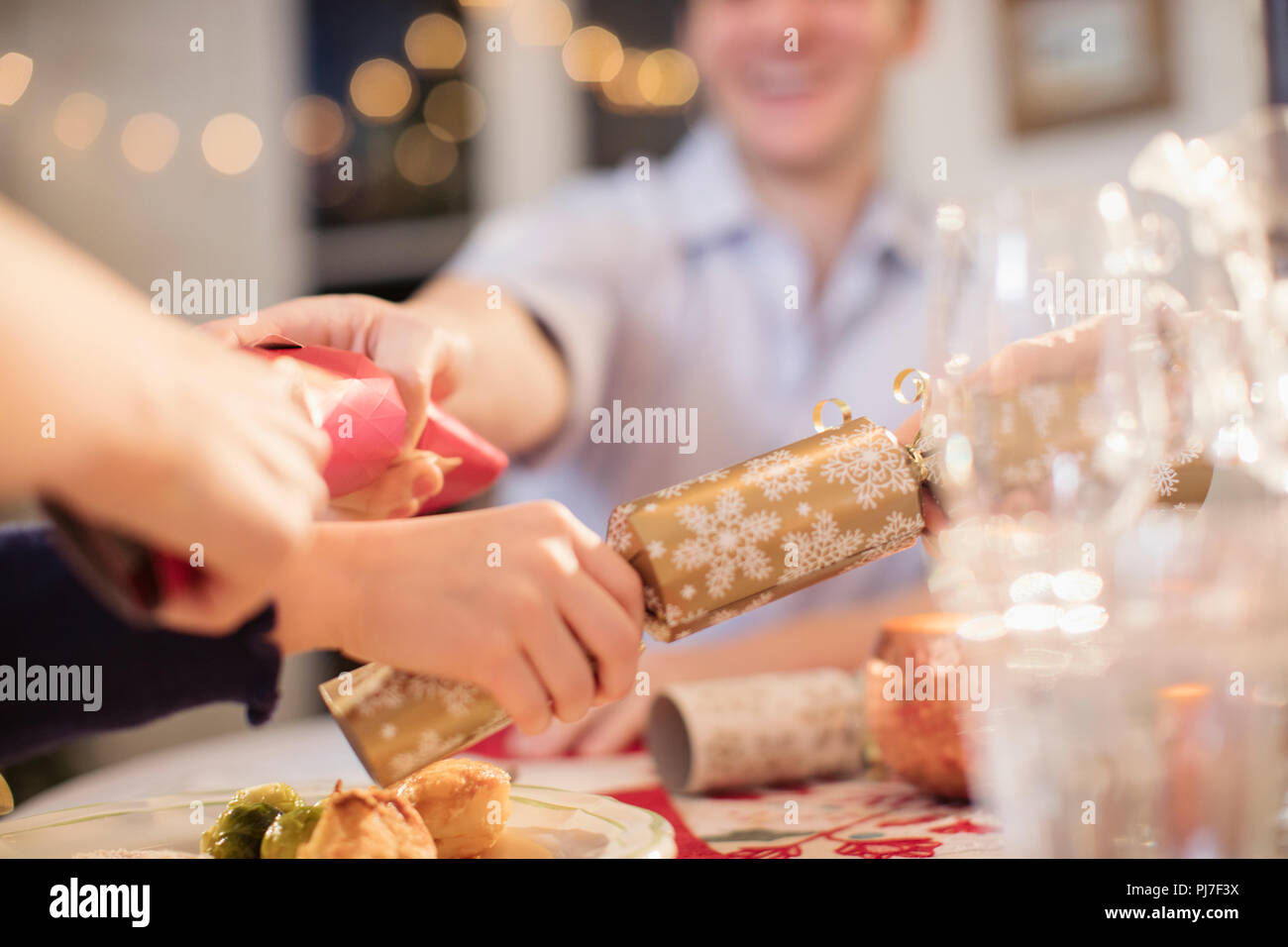 Family pulling Christmas crackers at dinner table Stock Photo