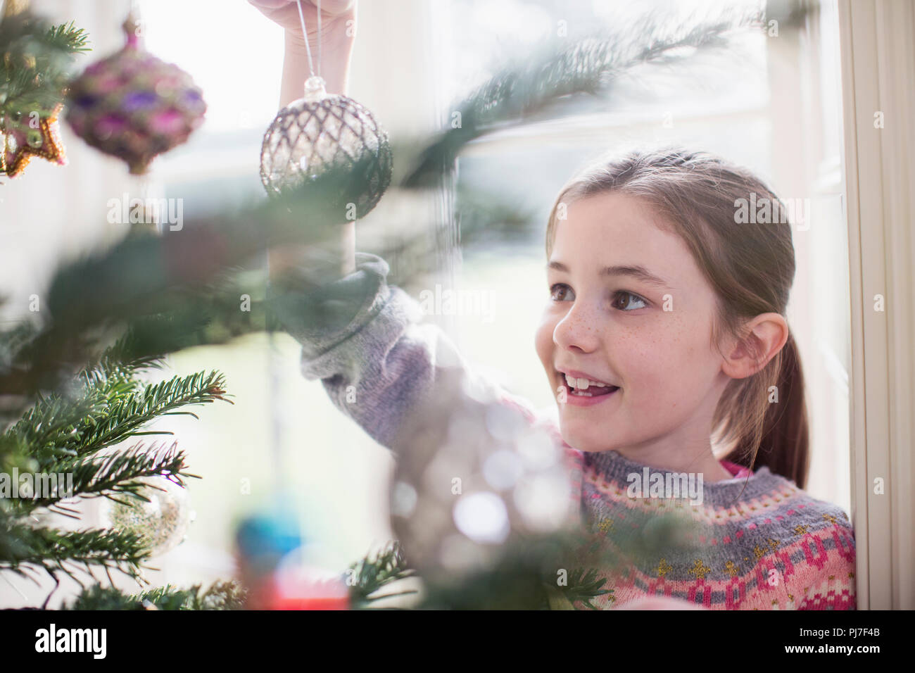 Girl decorating, hanging ornament on Christmas tree Stock Photo
